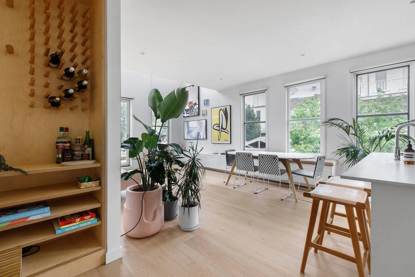 Un comedor luminoso con una mesa, asientos y ventanas grandes.