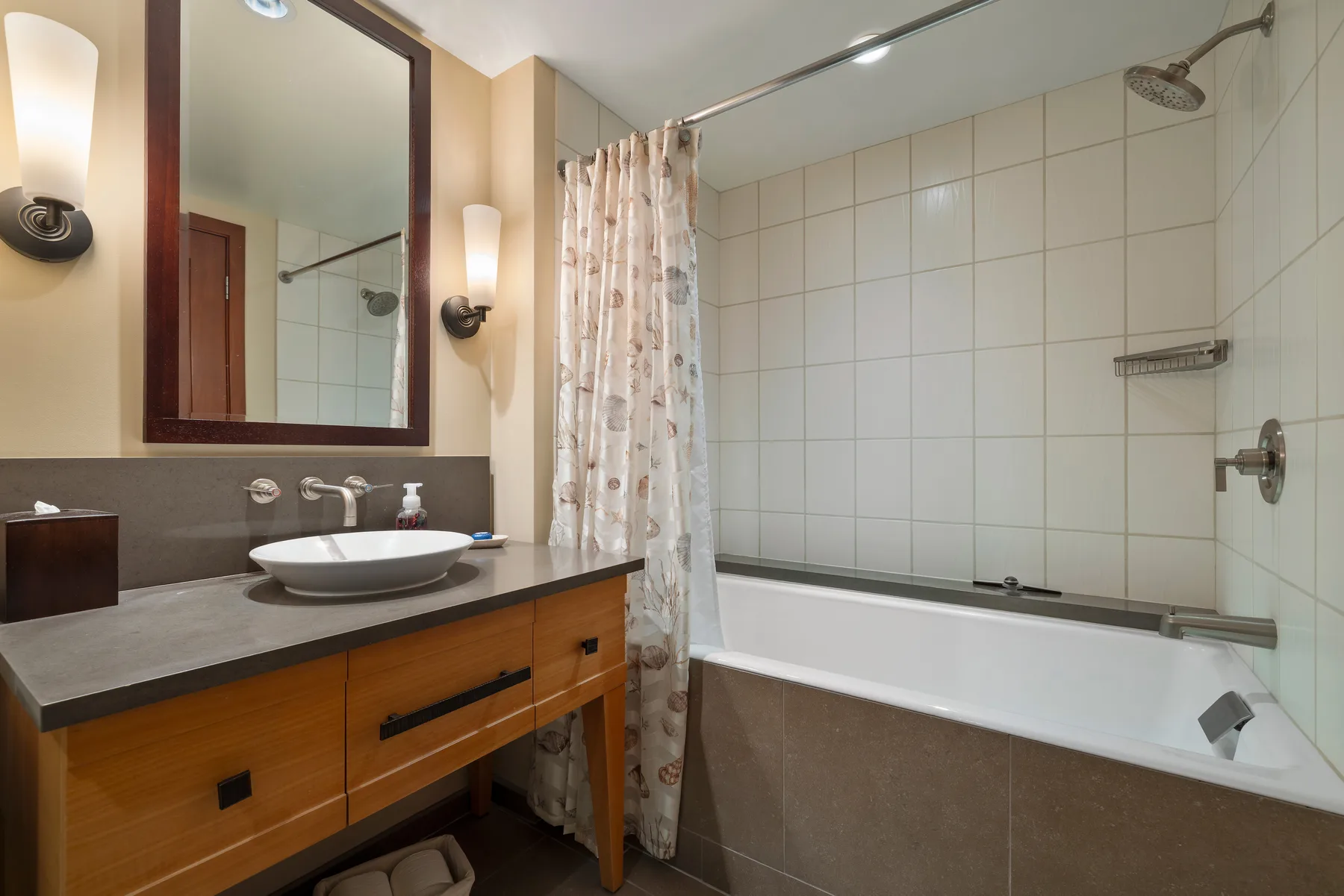 Un baño con lavabo y mueble, y una bañera detrás de una cortina de ducha.