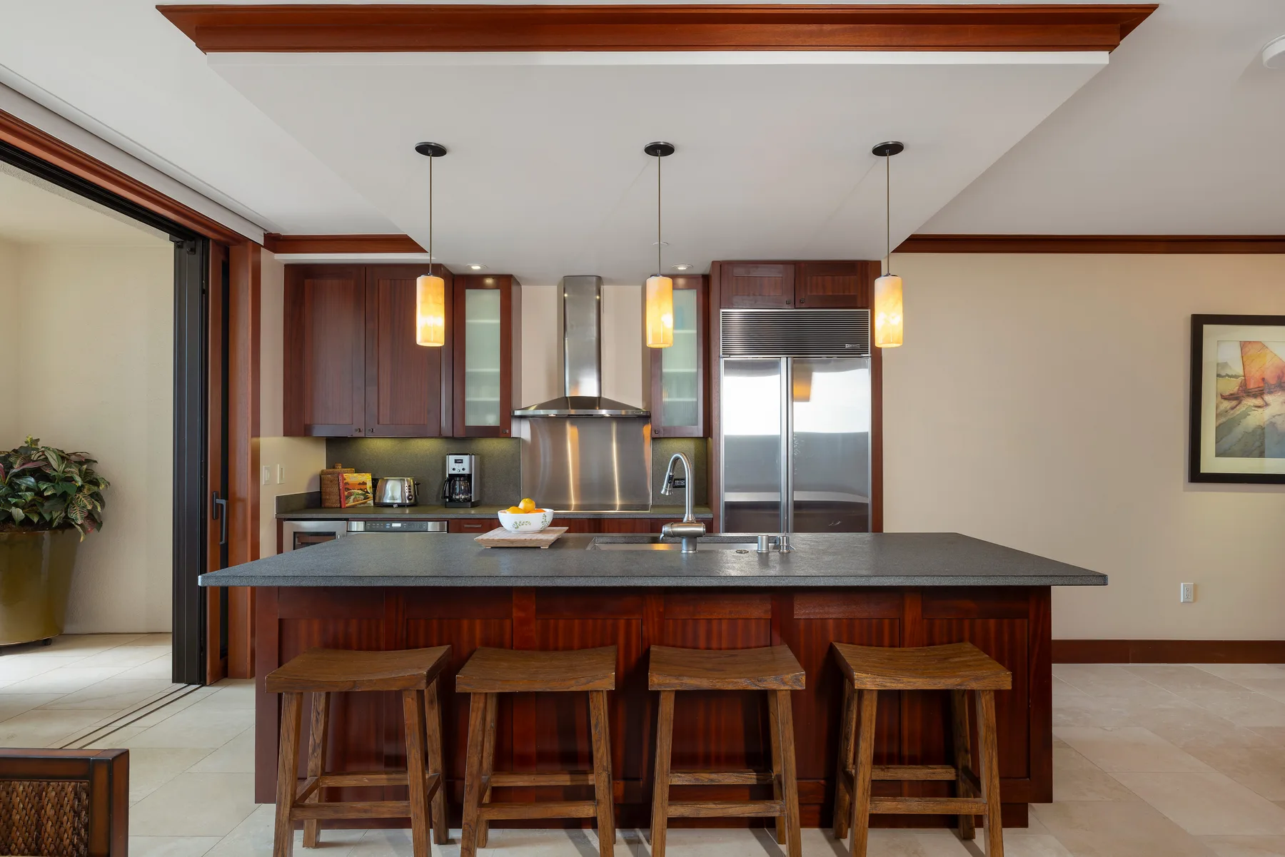 Una cocina con una isla central y taburetes de madera.