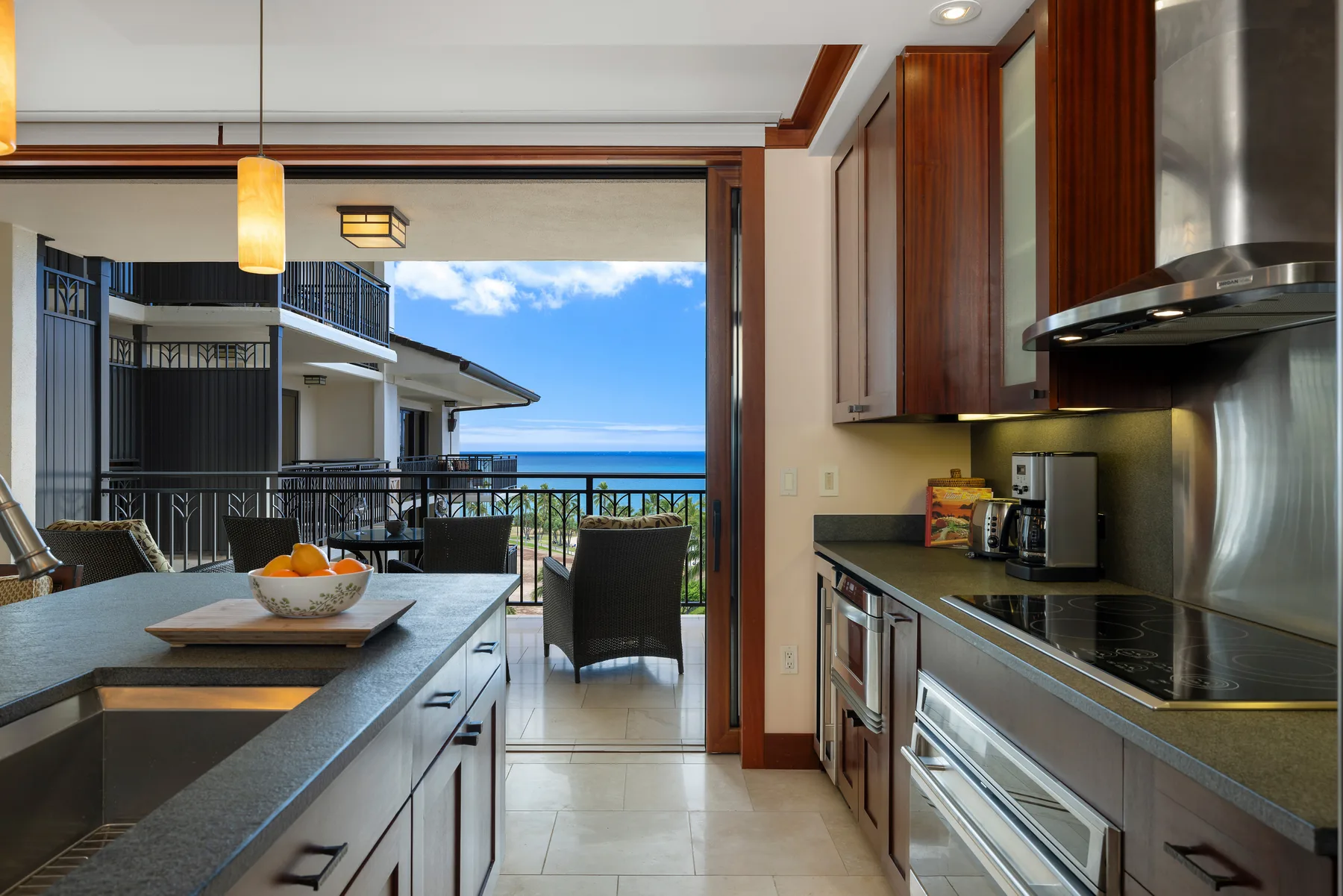 Una cocina abierta con una barra de comedor da a un balcón y al mar azul.