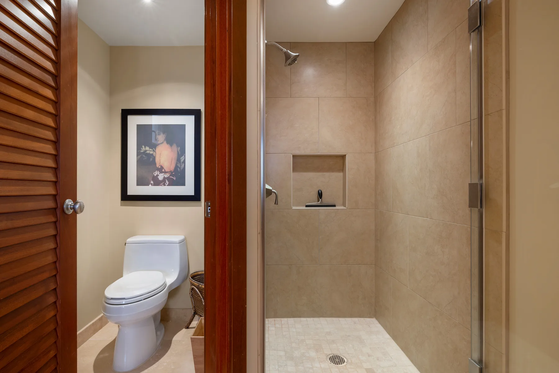 Un baño con un inodoro junto a una ducha revestida de azulejos.