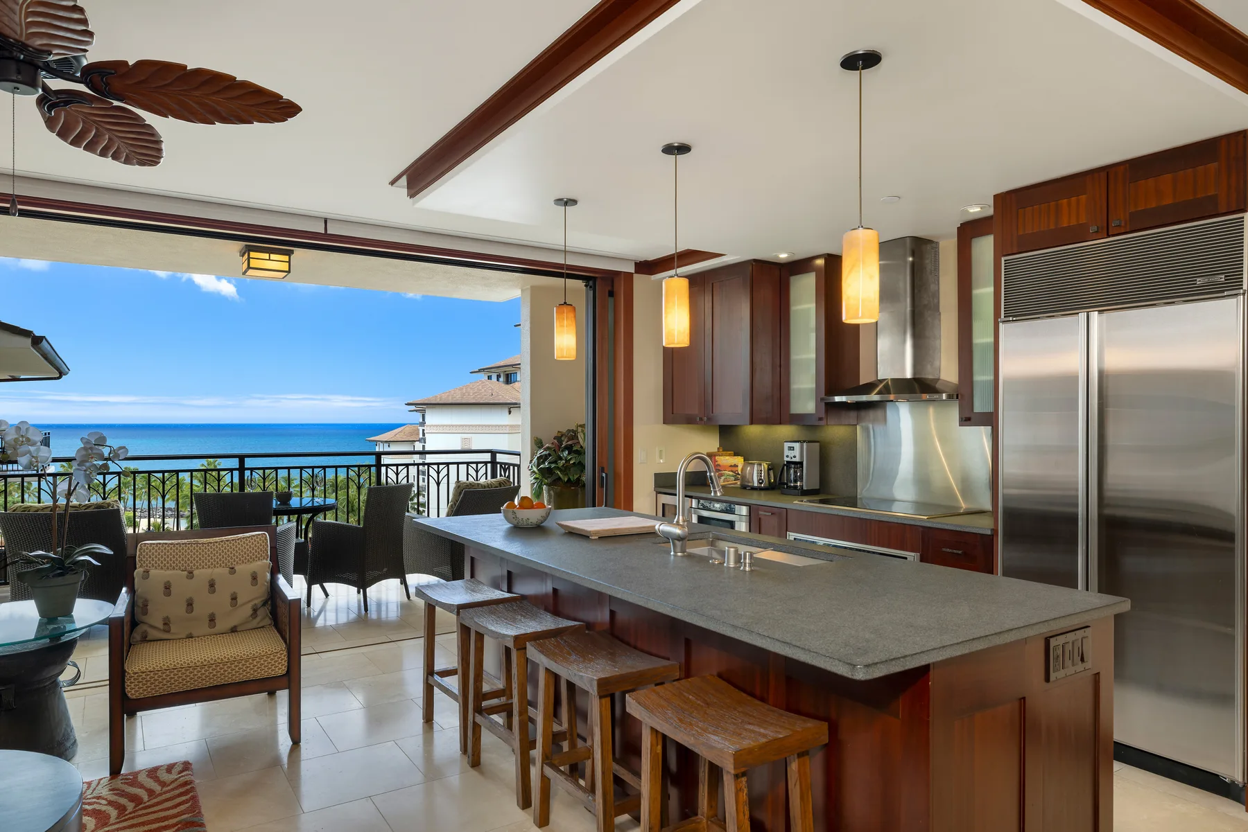 Una cocina moderna con una gran isla da a un balcón con vistas al océano.