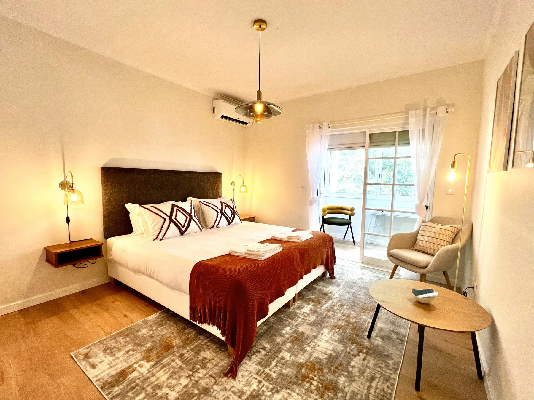 Dormitorio con cama doble, mesillas y una zona de estar junto a la ventana.