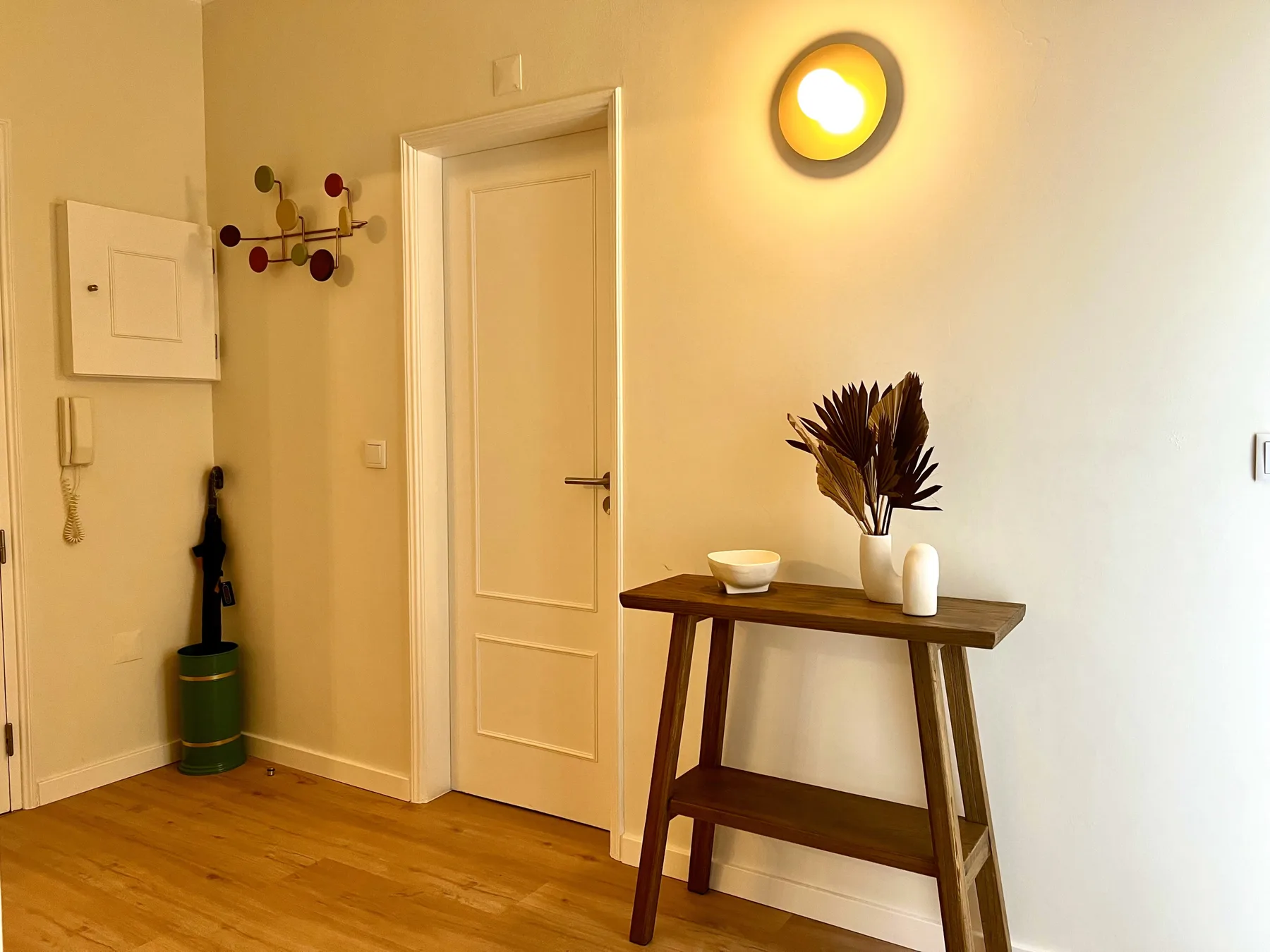 Una entrada de apartamento con una puerta cerrada y una consola estrecha.