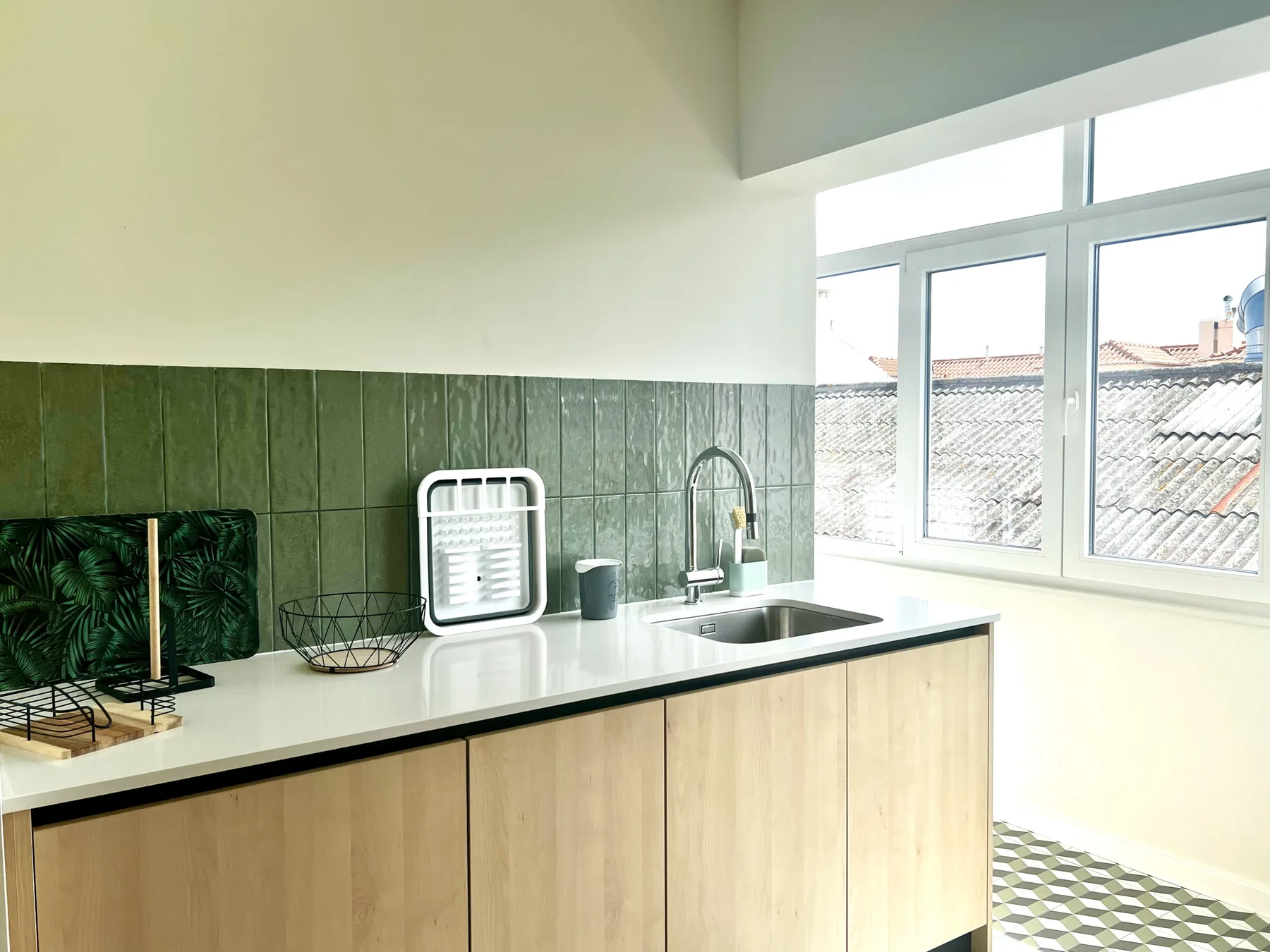 Una cocina luminosa con fregadero, encimera y ventanas grandes.