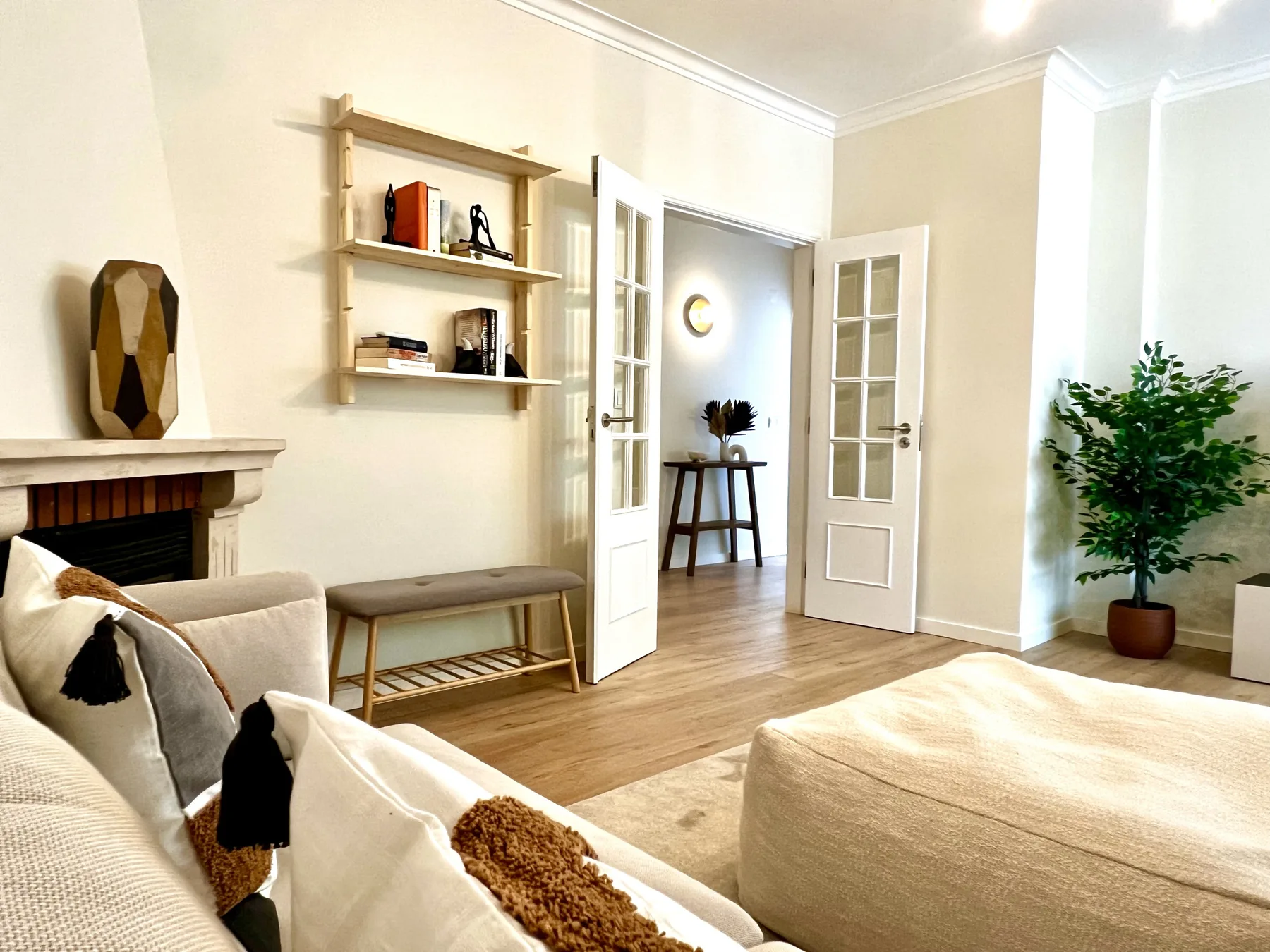 Una sala luminosa con asientos, una chimenea y puertas abiertas.