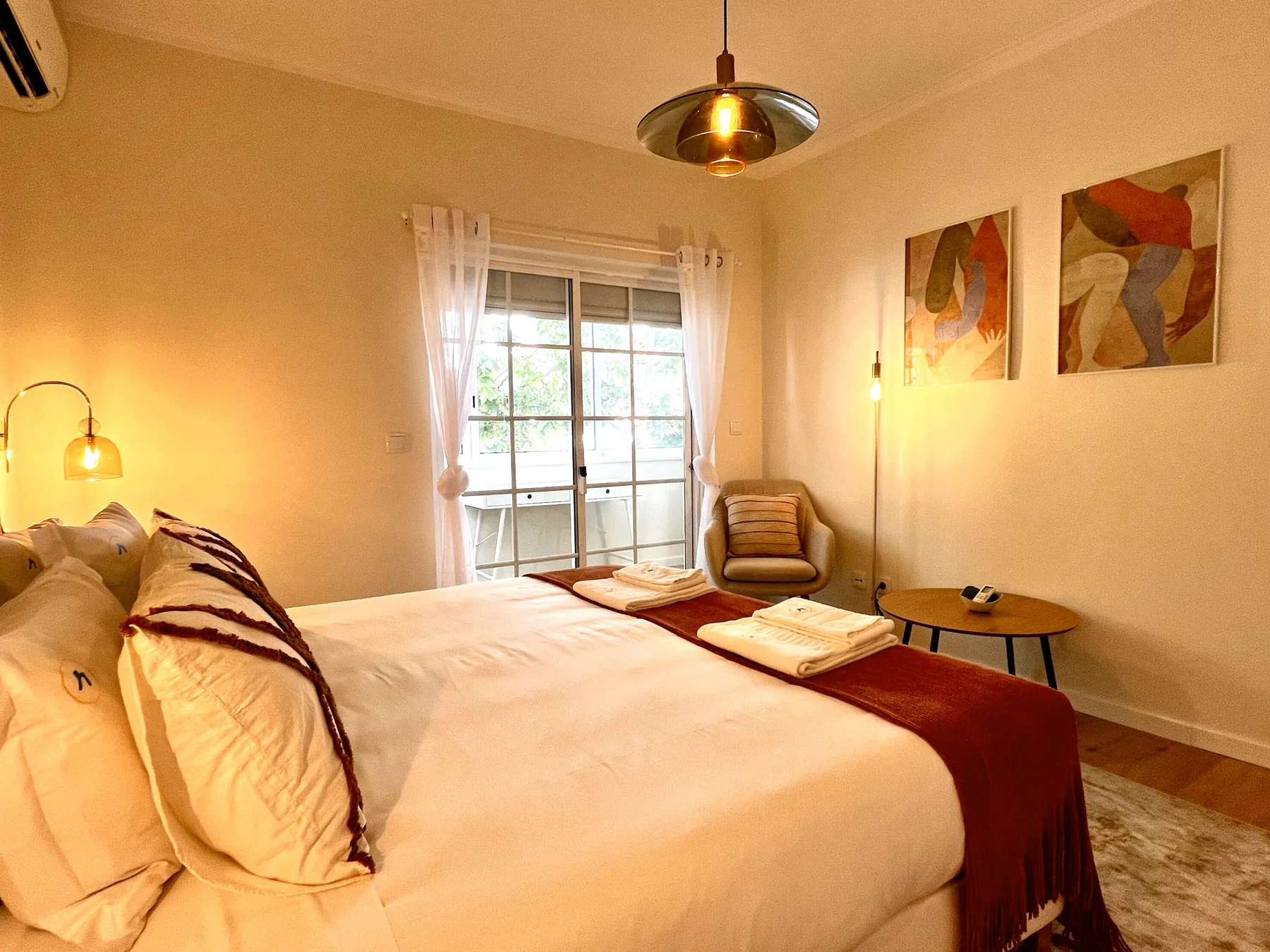 Un dormitorio con una cama grande, una ventana y arte abstracto en la pared.