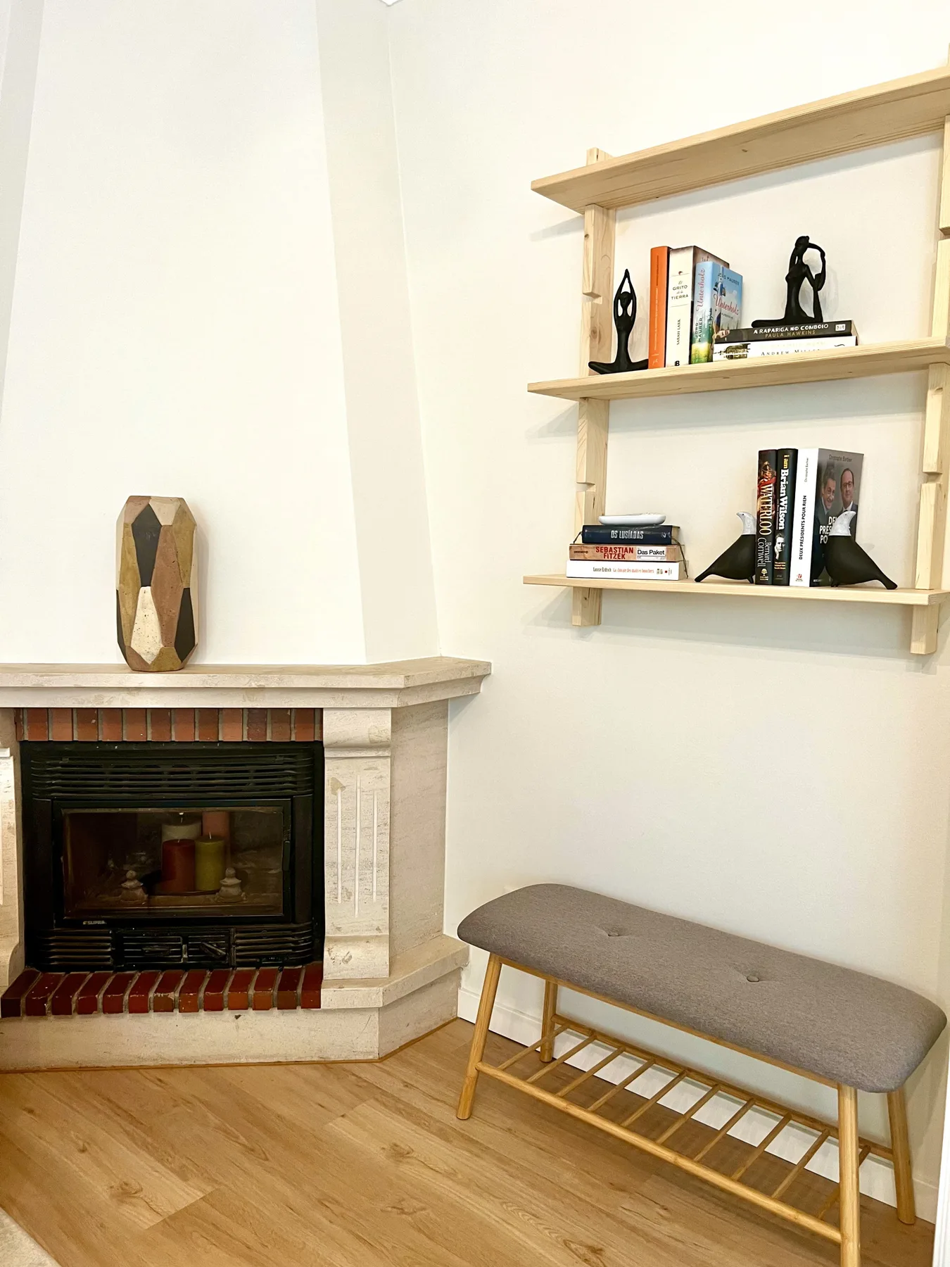 Una sala de estar cuenta con una chimenea, estantes de pared y un banco acolchado.