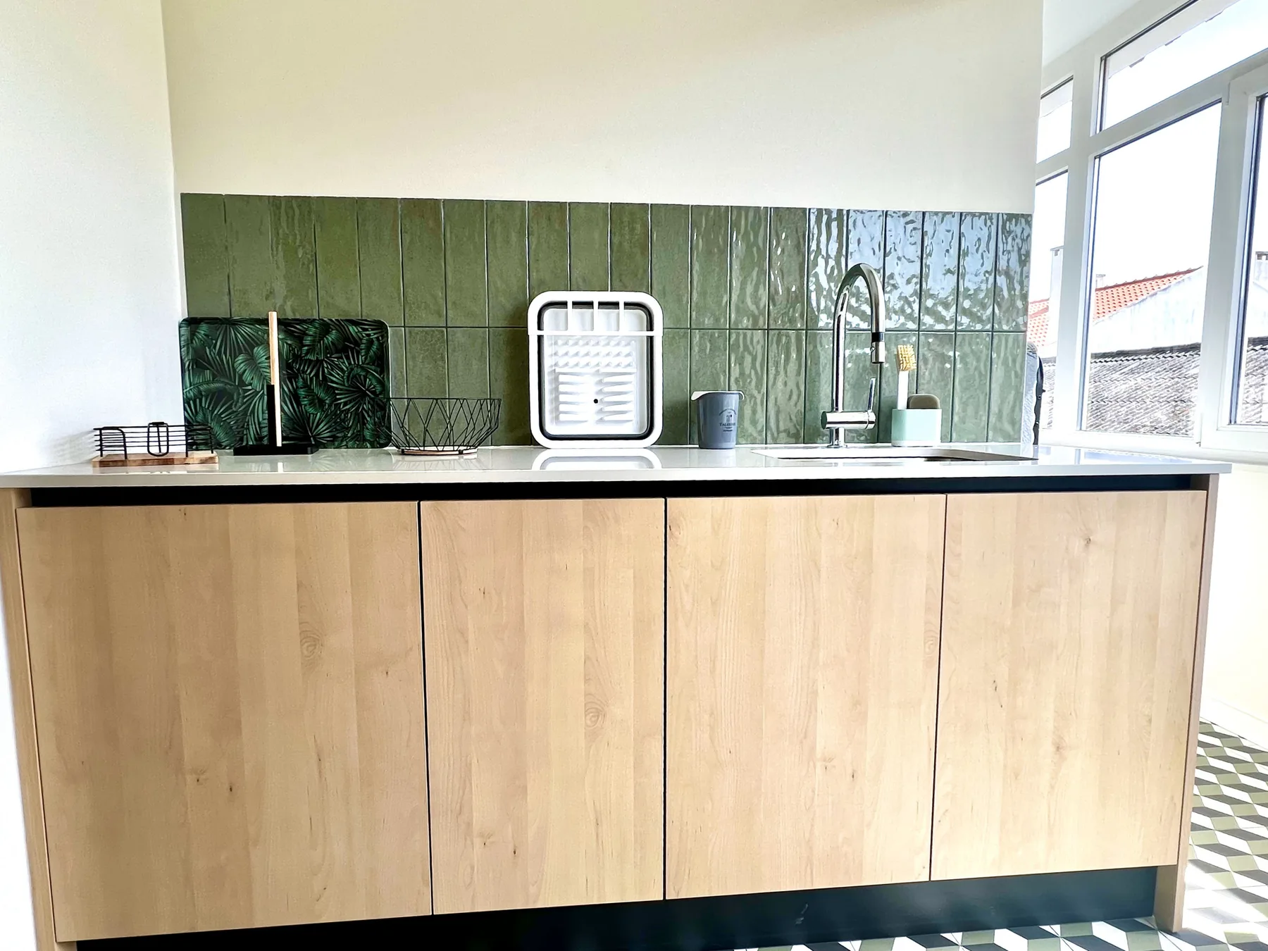 Una cocina luminosa con armarios de madera clara, una encimera y un fregadero.