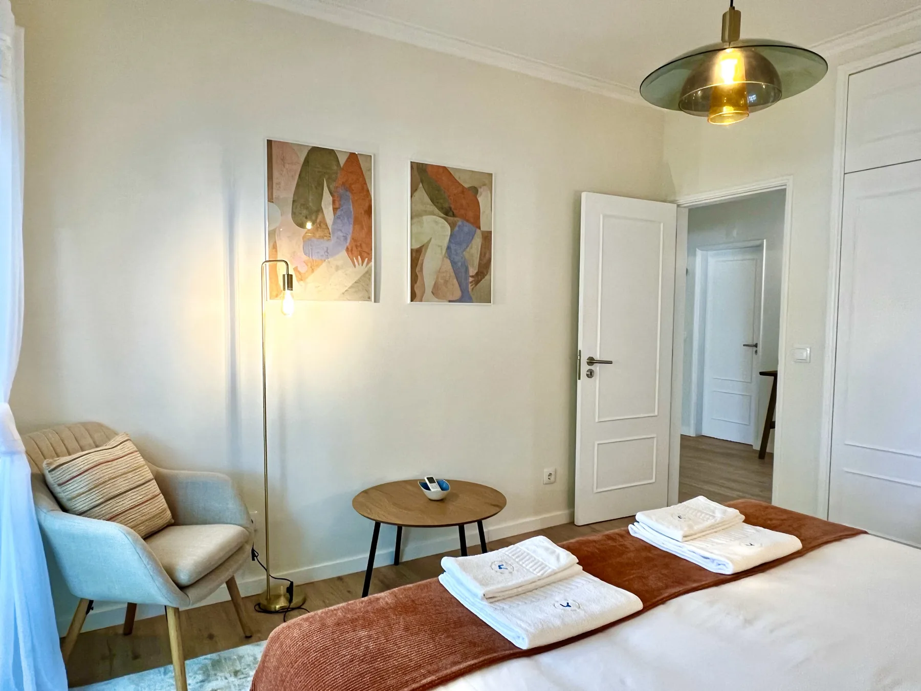 Dormitorio con una cama bien tendida, toallas dobladas y una pequeña zona de estar.