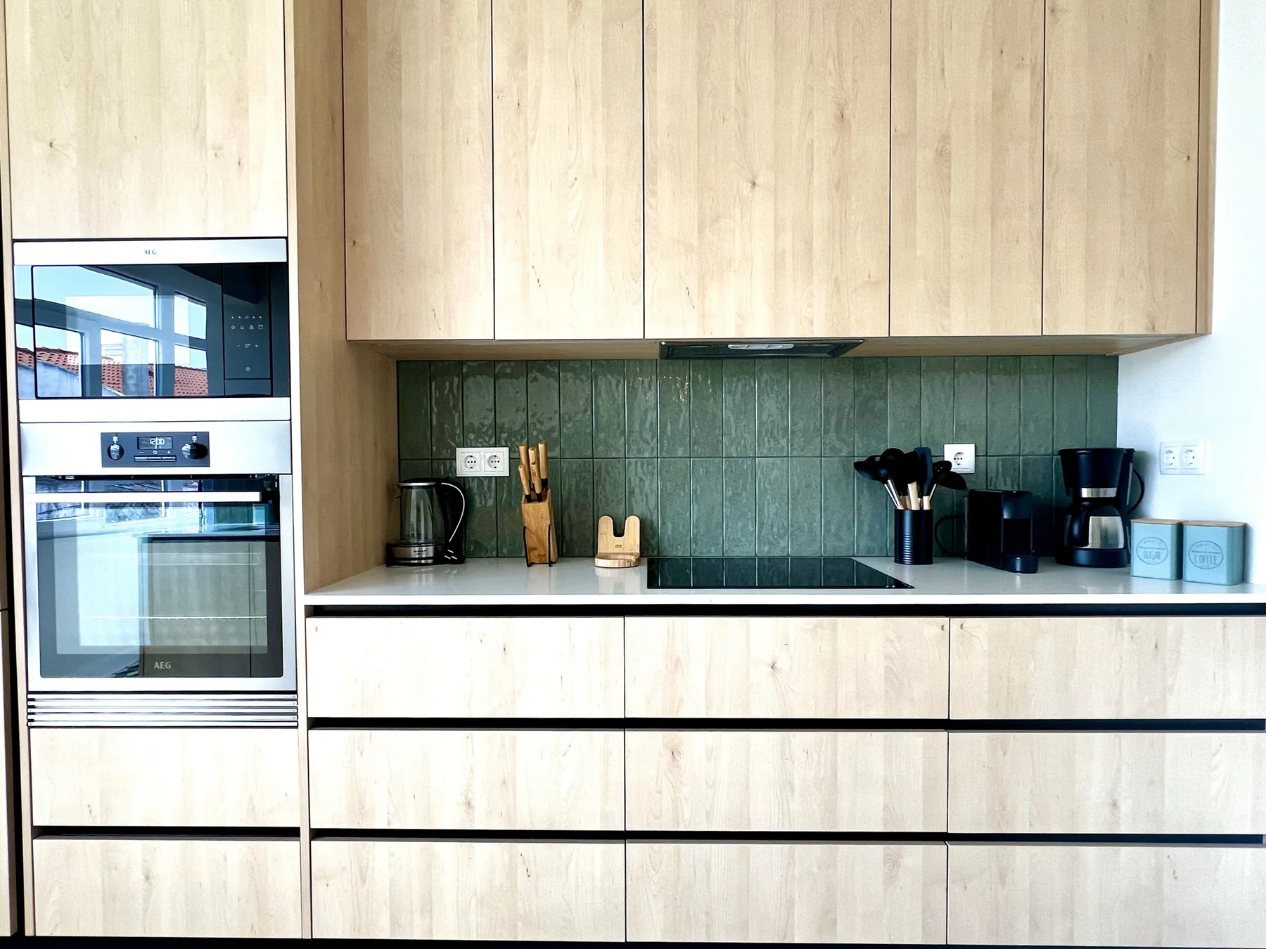Una cocina moderna con gabinetes claros, una encimera oscura y electrodomésticos integrados.