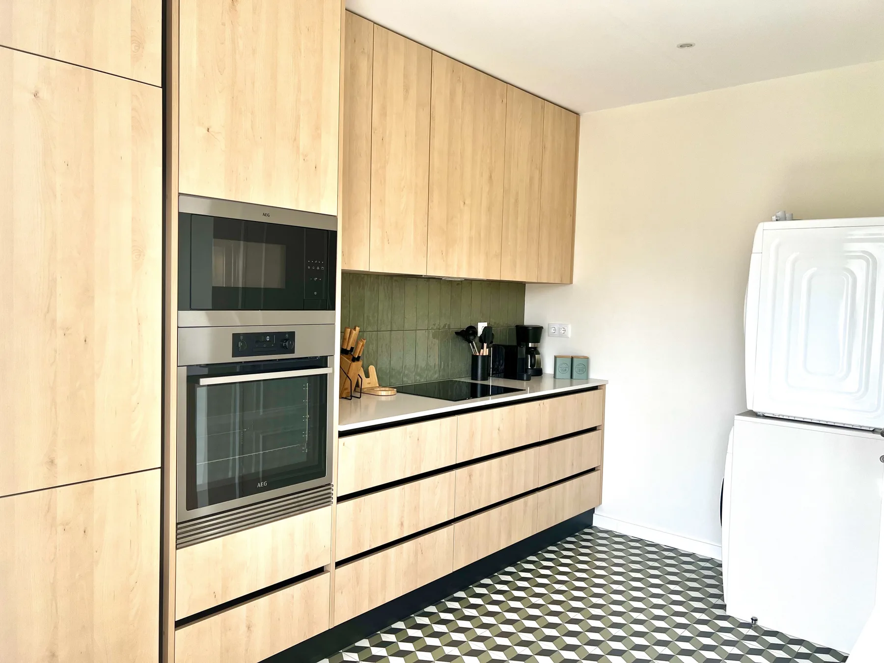 Una cocina moderna con armarios de madera clara y electrodomésticos integrados.