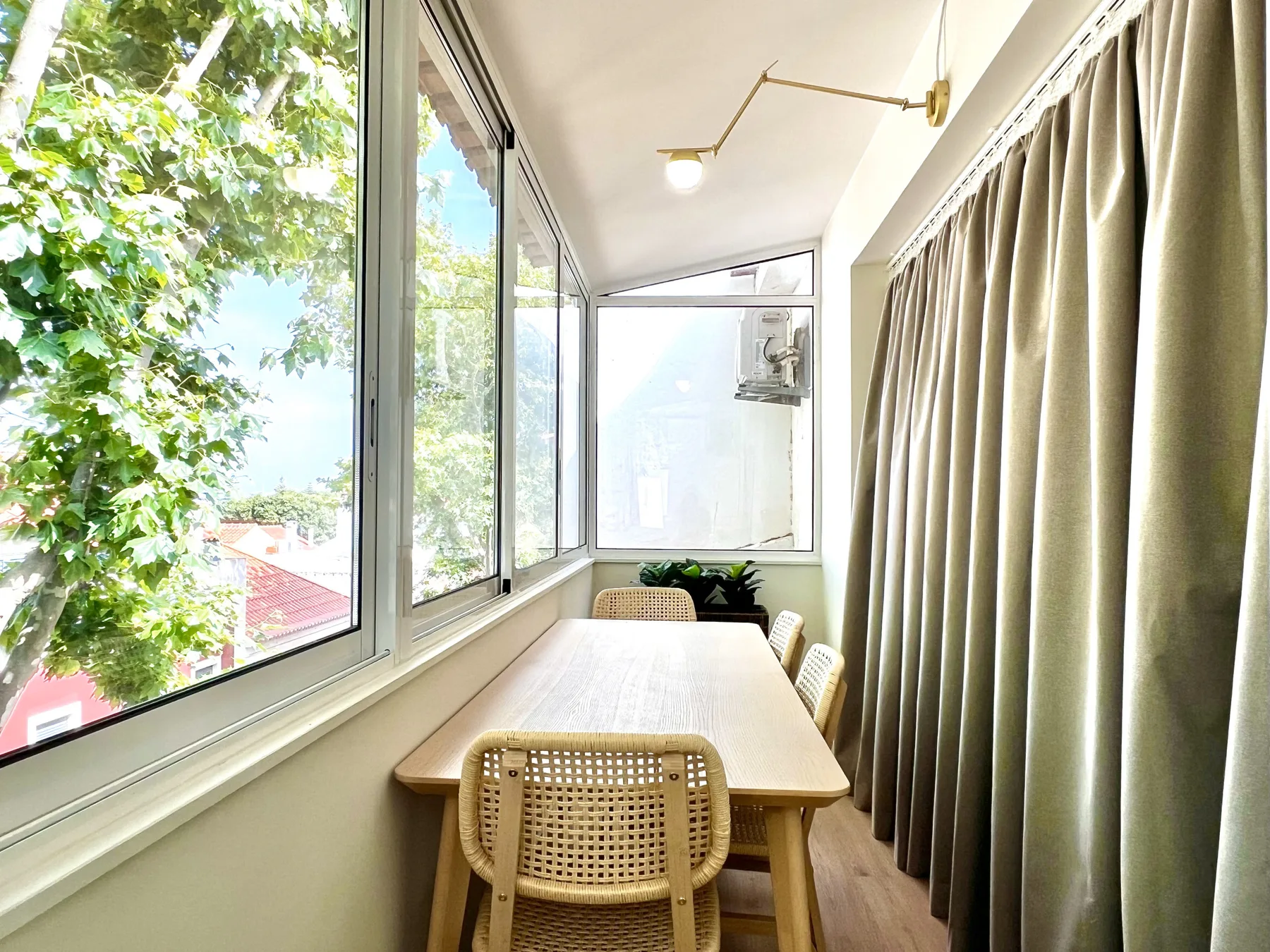 Un comedor luminoso con una mesa de madera junto a grandes ventanas y cortinas.