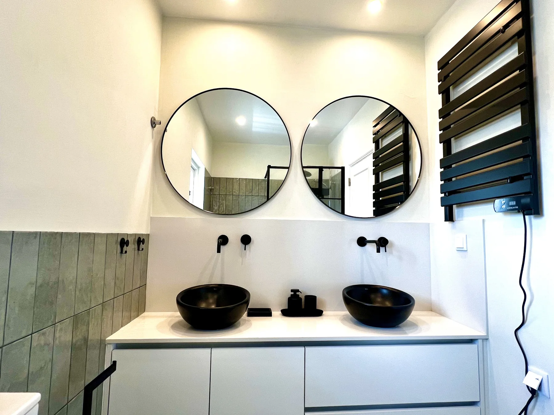 Un lavabo de baño con dos espejos redondos y lavabos oscuros sobre la encimera.