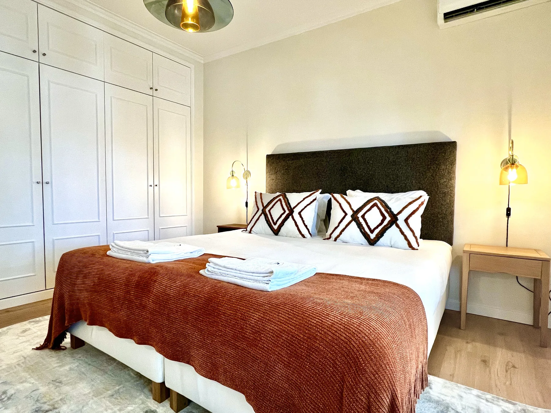 Un dormitorio con una cama bien hecha, almohadas estampadas y armarios empotrados.