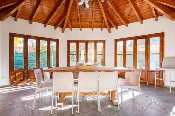 Comedor con una mesa larga y asientos bajo un techo de madera.