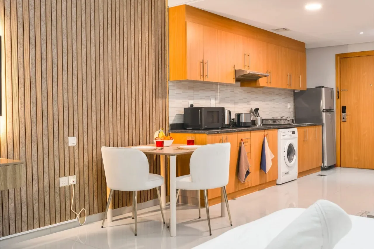 A kitchen and dining area with wooden cabinets, appliances, and a small table.