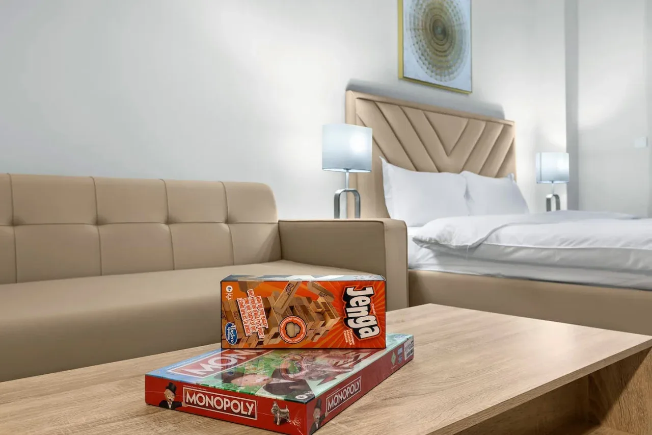 A bedroom with a bed, upholstered seating, and board games on a table.