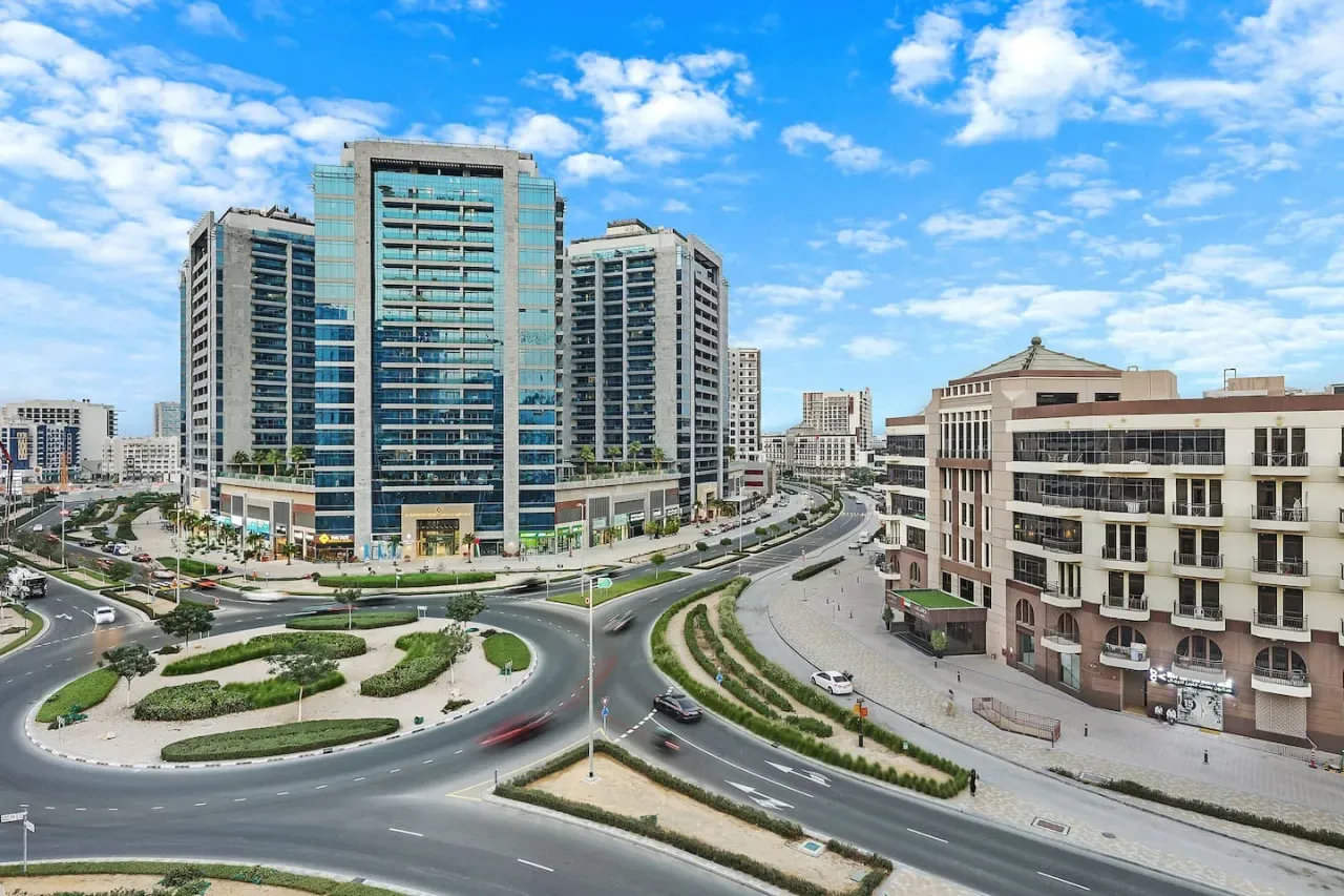 A city intersection curves around landscaped medians, with high-rise buildings nearby.