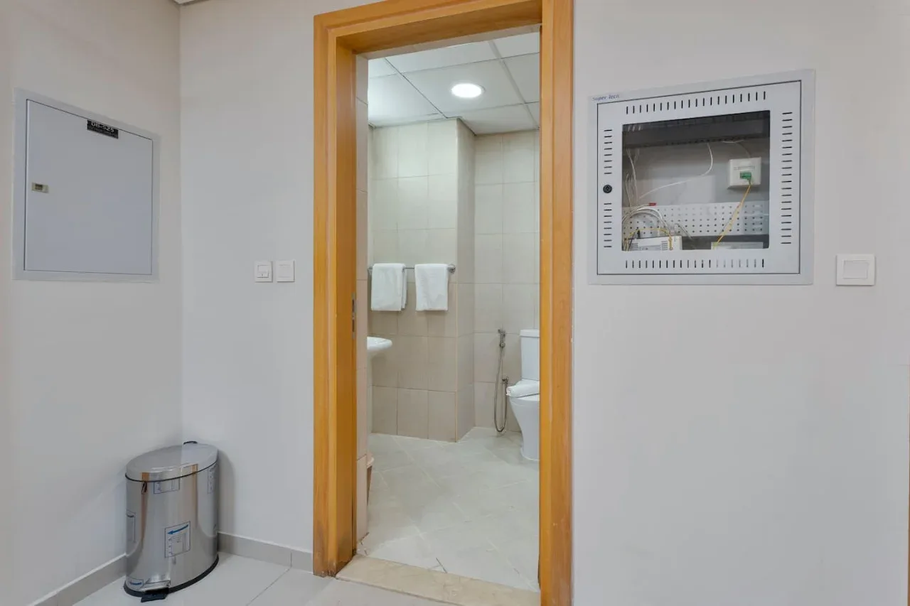 A bathroom is visible through a wooden doorway, with towels on the wall.