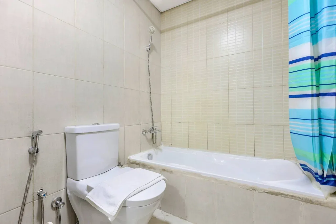 A tiled bathroom with a bathtub, toilet, and striped shower curtain.