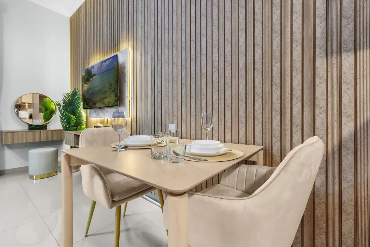 A dining area with a set table, upholstered seating, and a wall-mounted television.