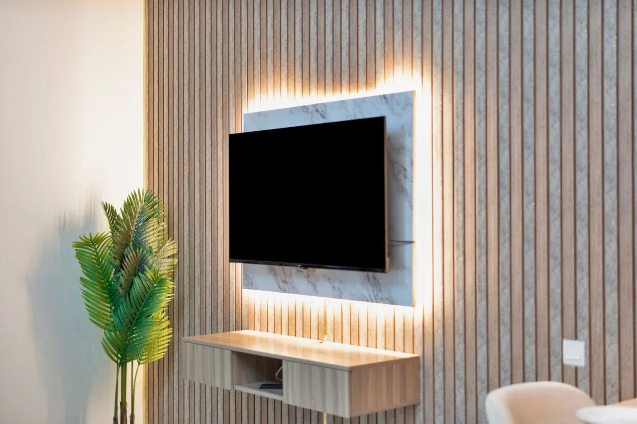 A television hangs above a floating console against a slatted wall.