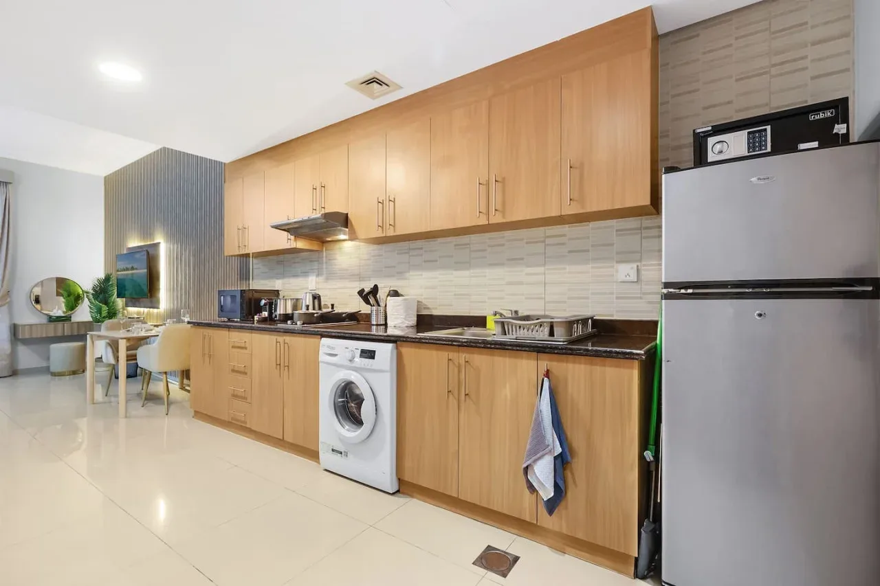 A bright kitchen with wooden cabinets, a countertop, and a refrigerator.
