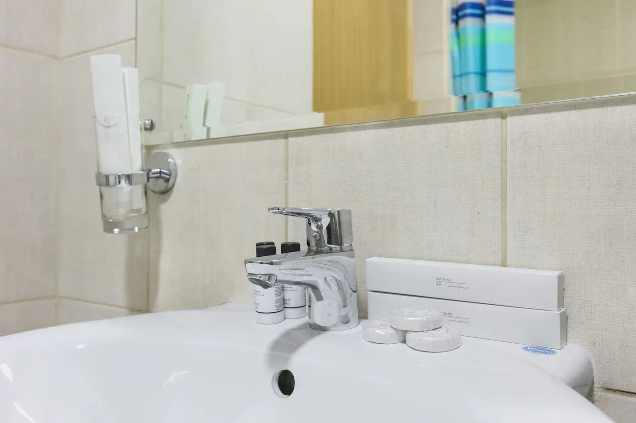 A bathroom sink with a chrome faucet and toiletries sits beneath a mirror.