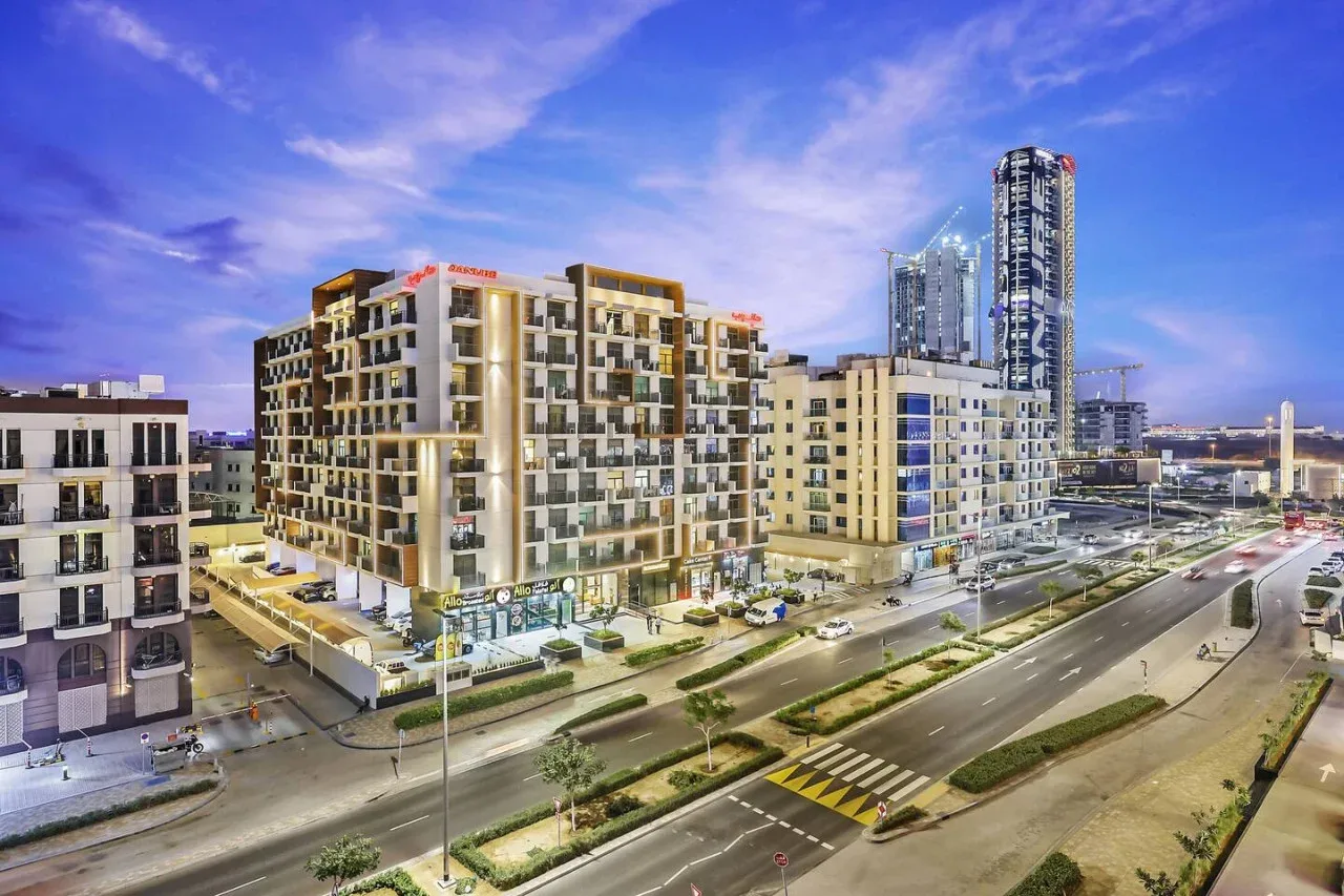 An urban streetscape with modern apartment buildings and a wide road at dusk.
