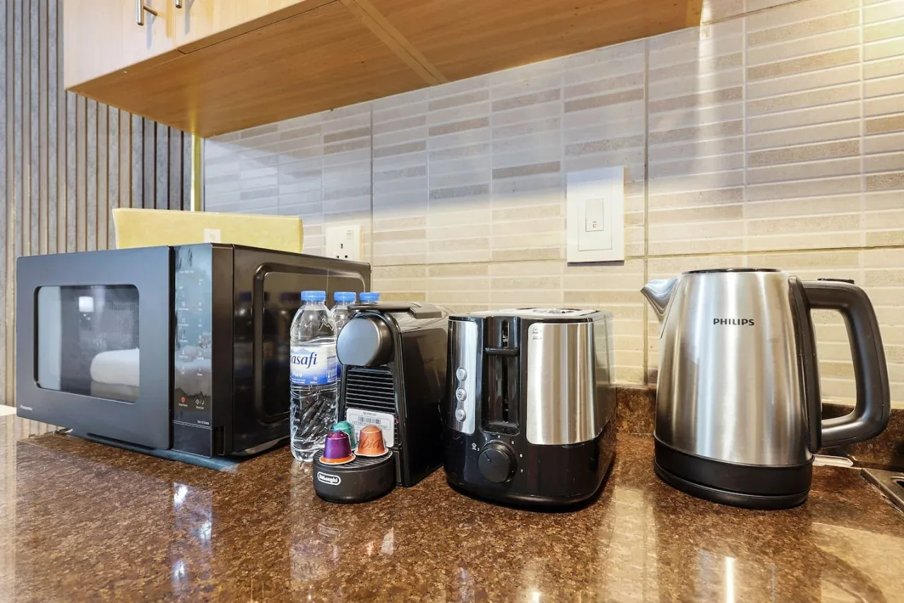 A kitchen counter with a microwave, coffee machine, and electric kettle.