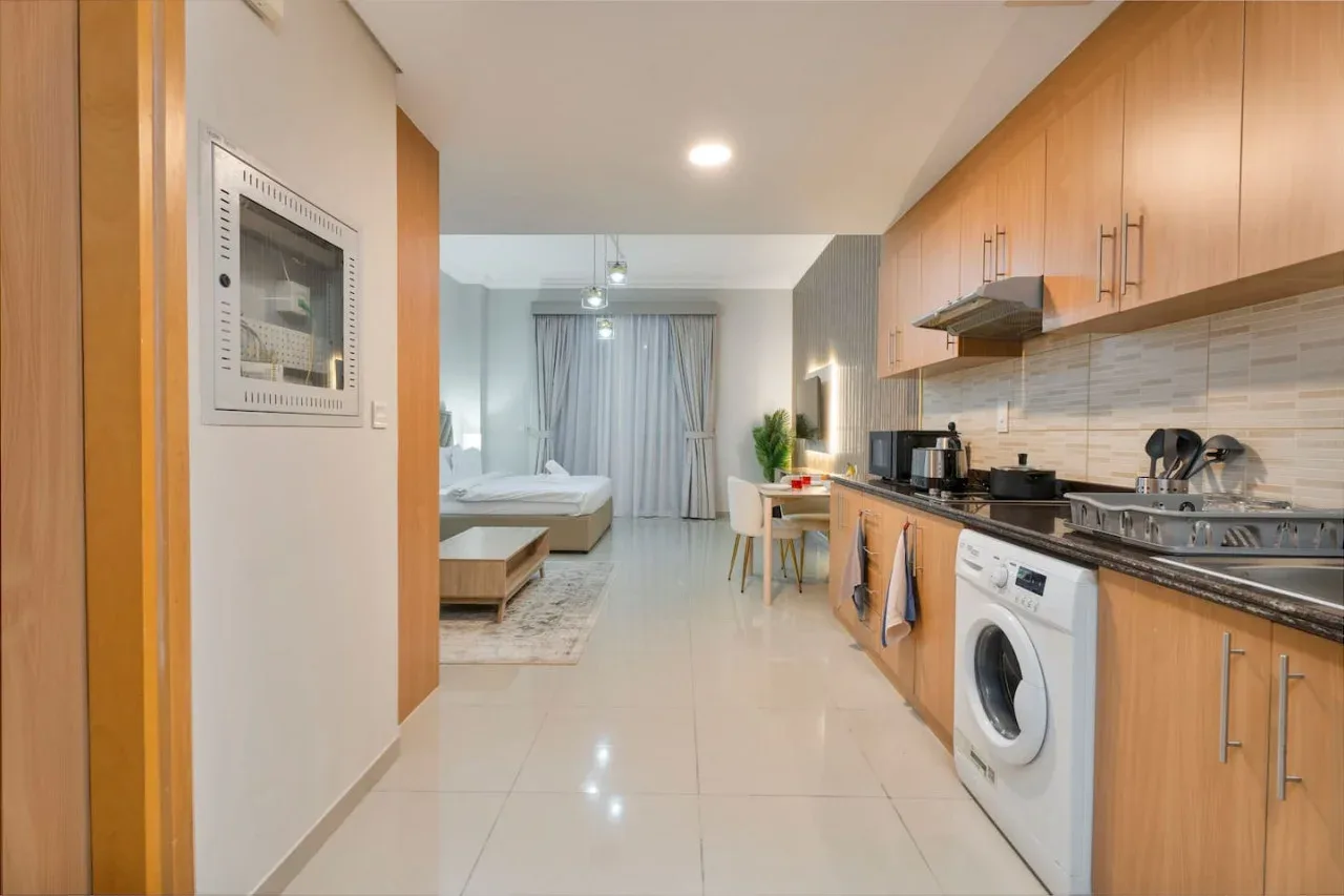 A compact kitchen opens onto a bedroom area, with a dining table beside the counter.