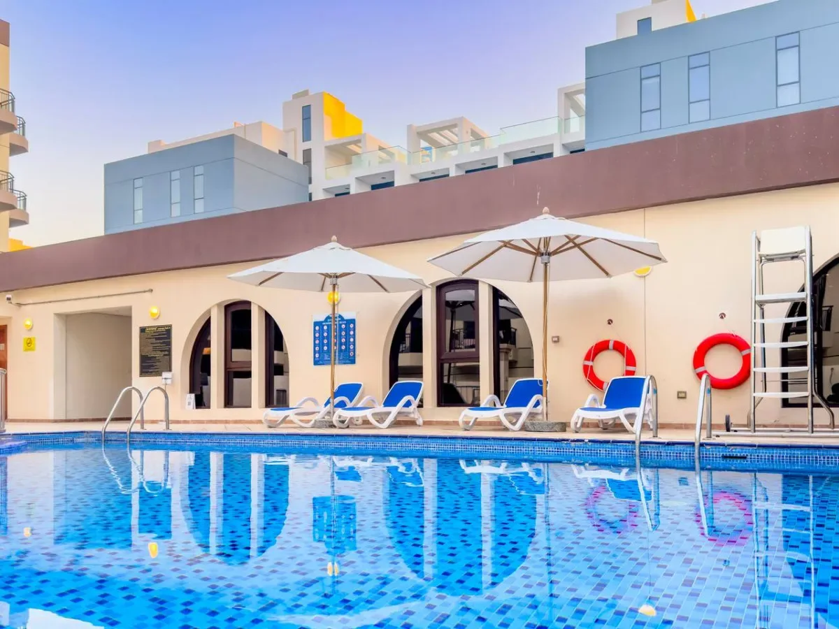 An outdoor swimming pool with lounge seating and umbrellas beside the water.
