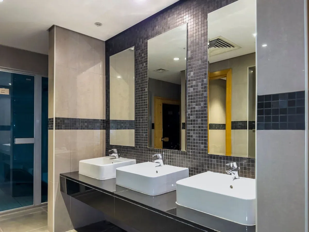 A modern bathroom vanity with three sinks and large wall mirrors.