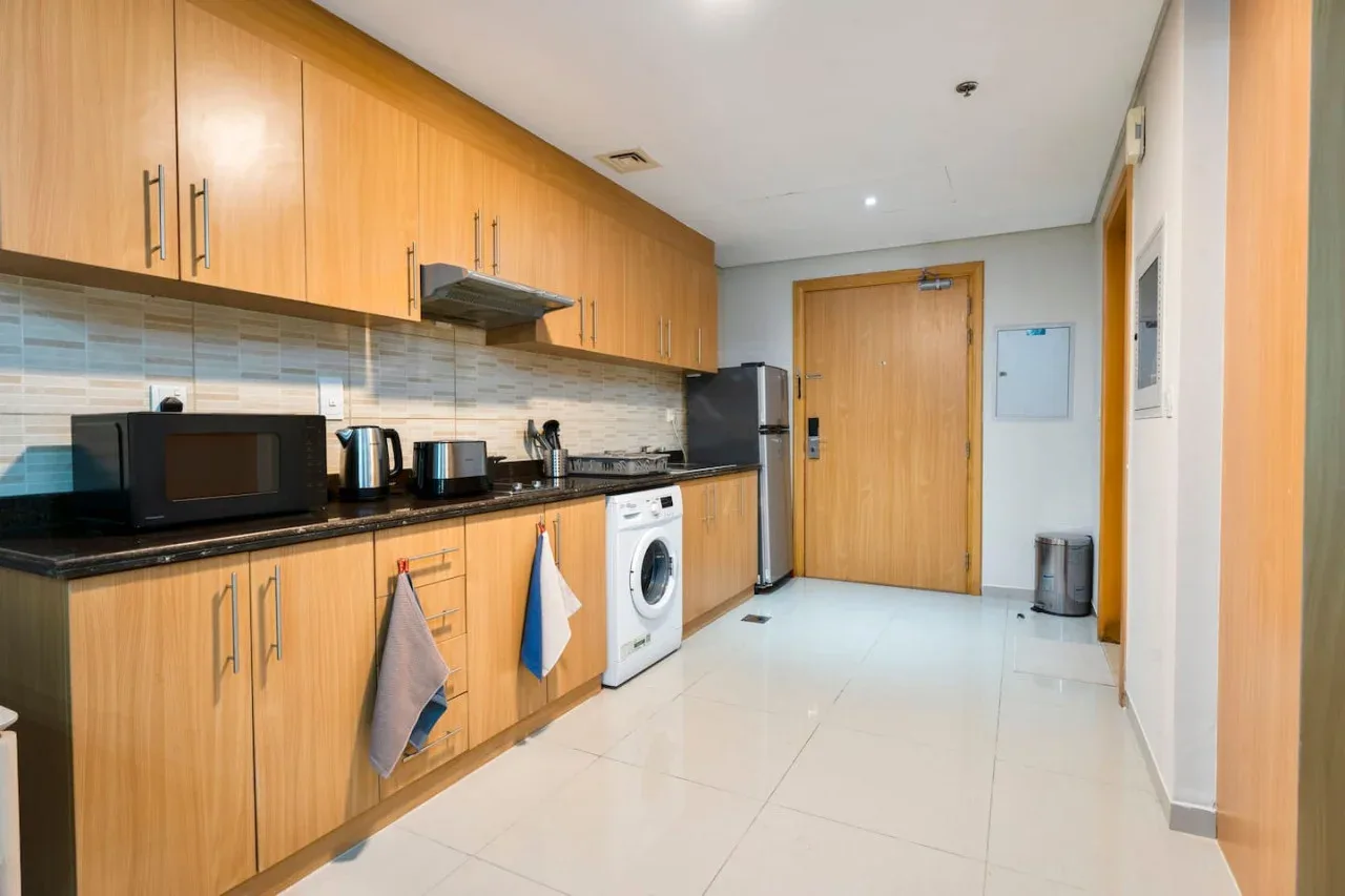 A compact kitchen with wooden cabinets, a countertop, and a washing machine.