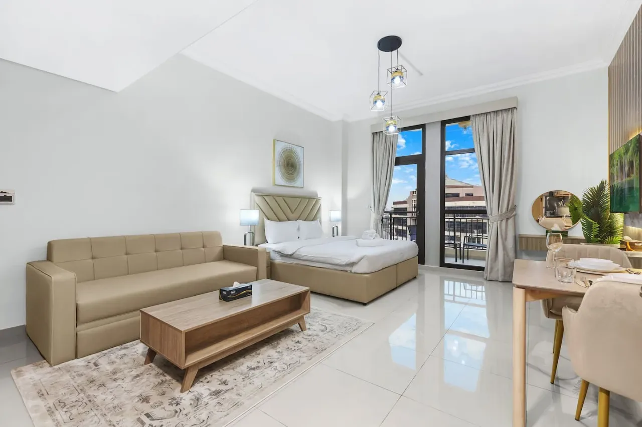 A bright bedroom with a bed, seating area, and glass doors opening to a balcony.