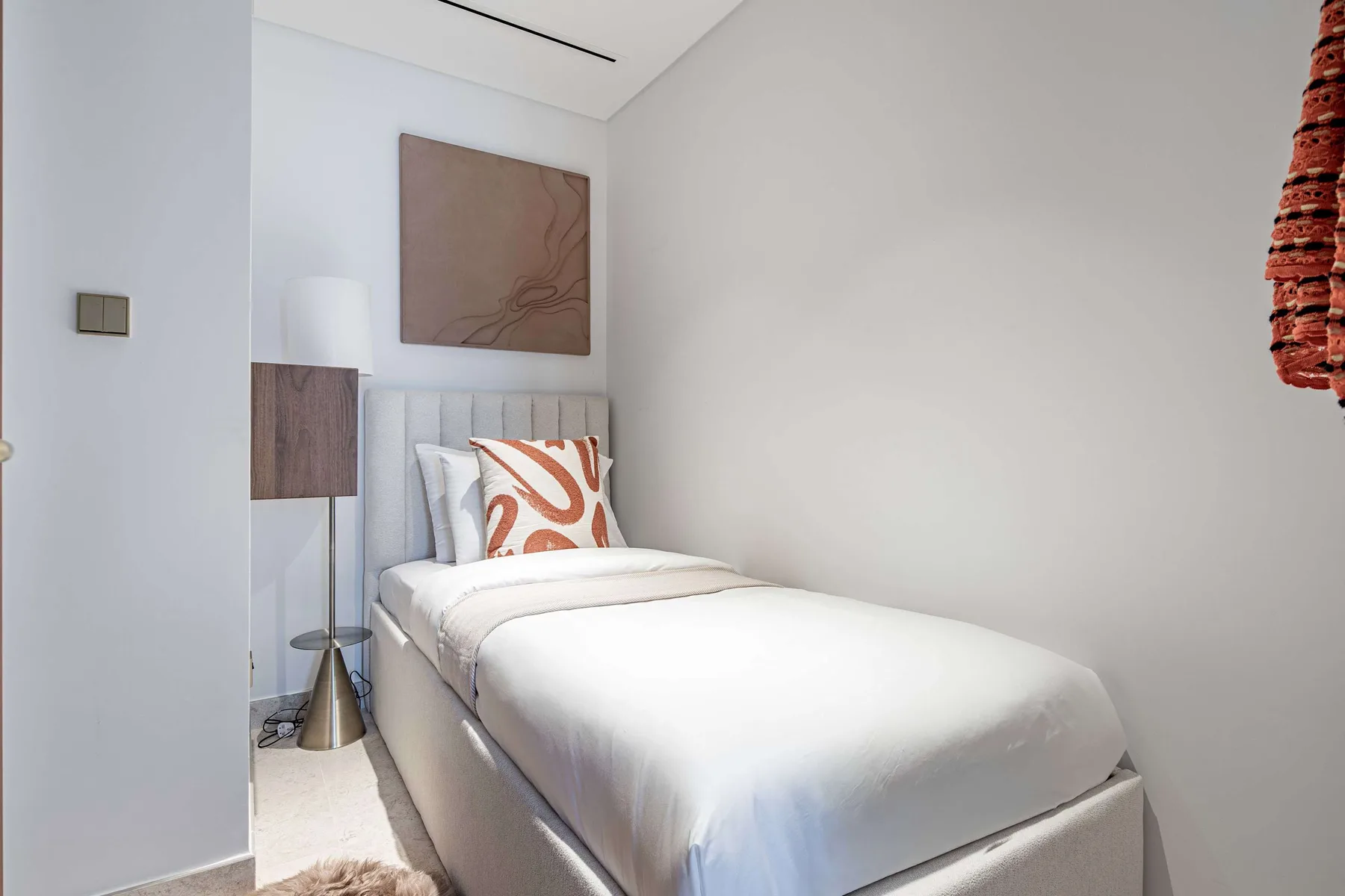 Un dormitorio con una cama bien tendida y un cojín decorativo.