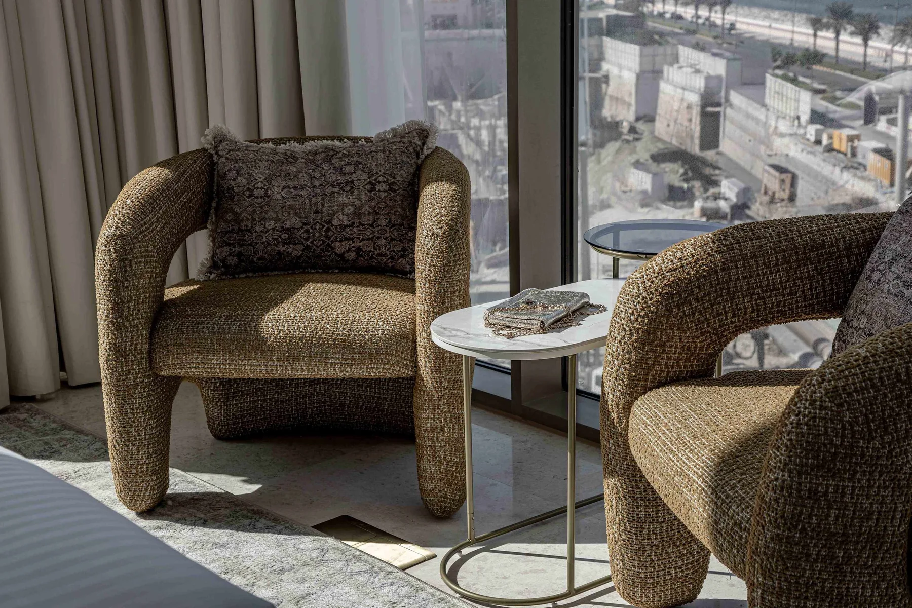 Zona de estar junto a grandes ventanales, con sillones tapizados y una mesa pequeña.