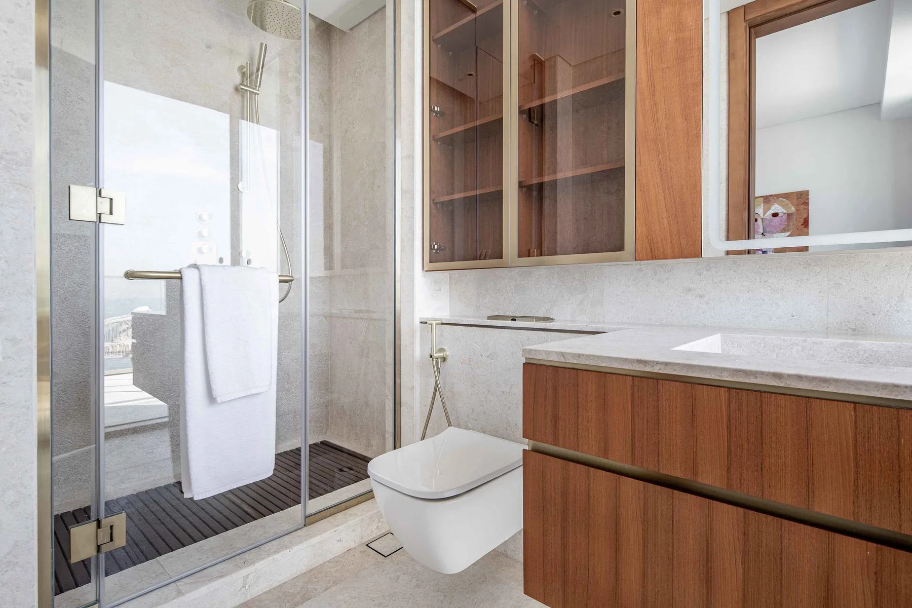 Un baño moderno con una ducha de vidrio y un mueble de madera.