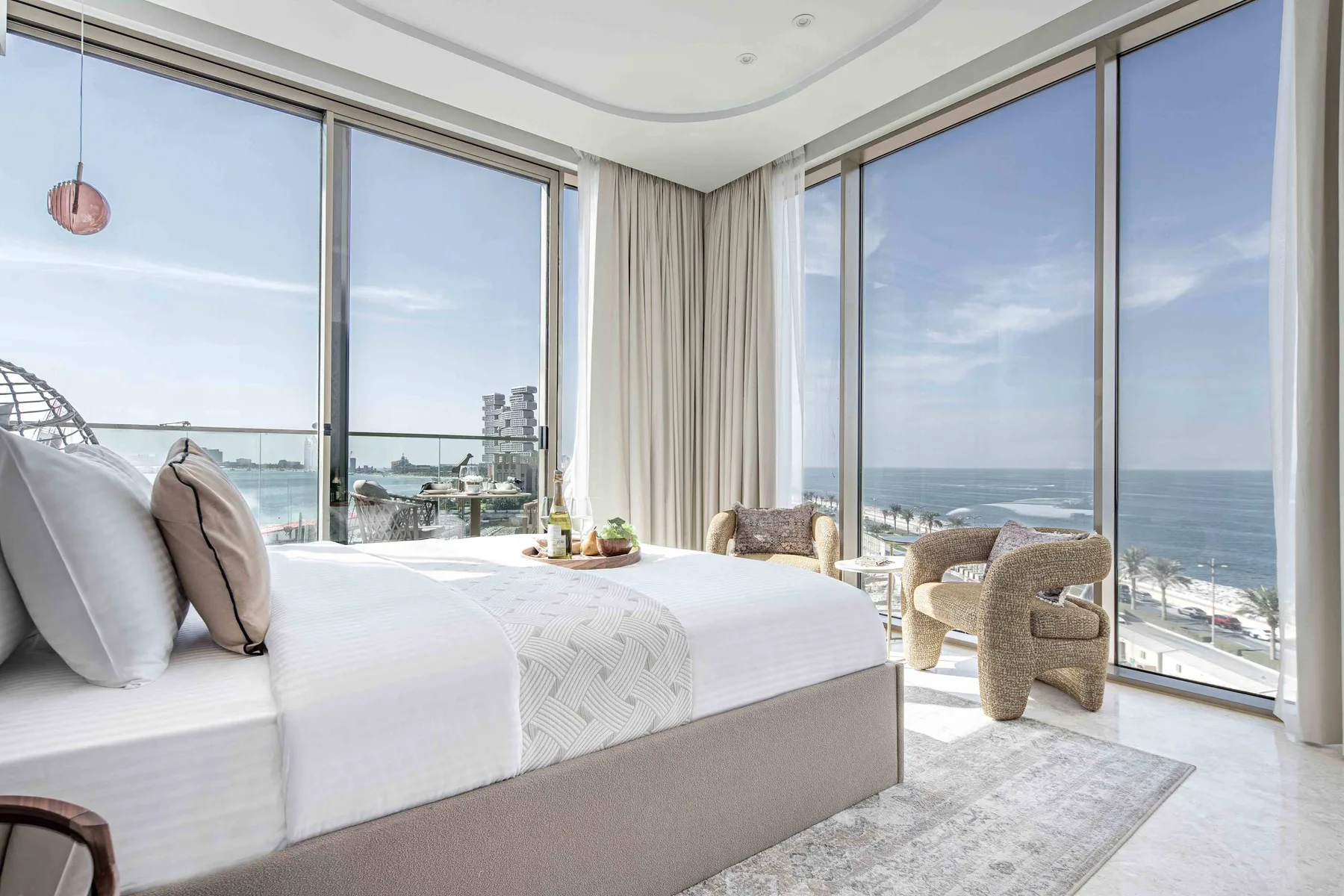 Un dormitorio luminoso con una cama junto a ventanales con vistas al mar.