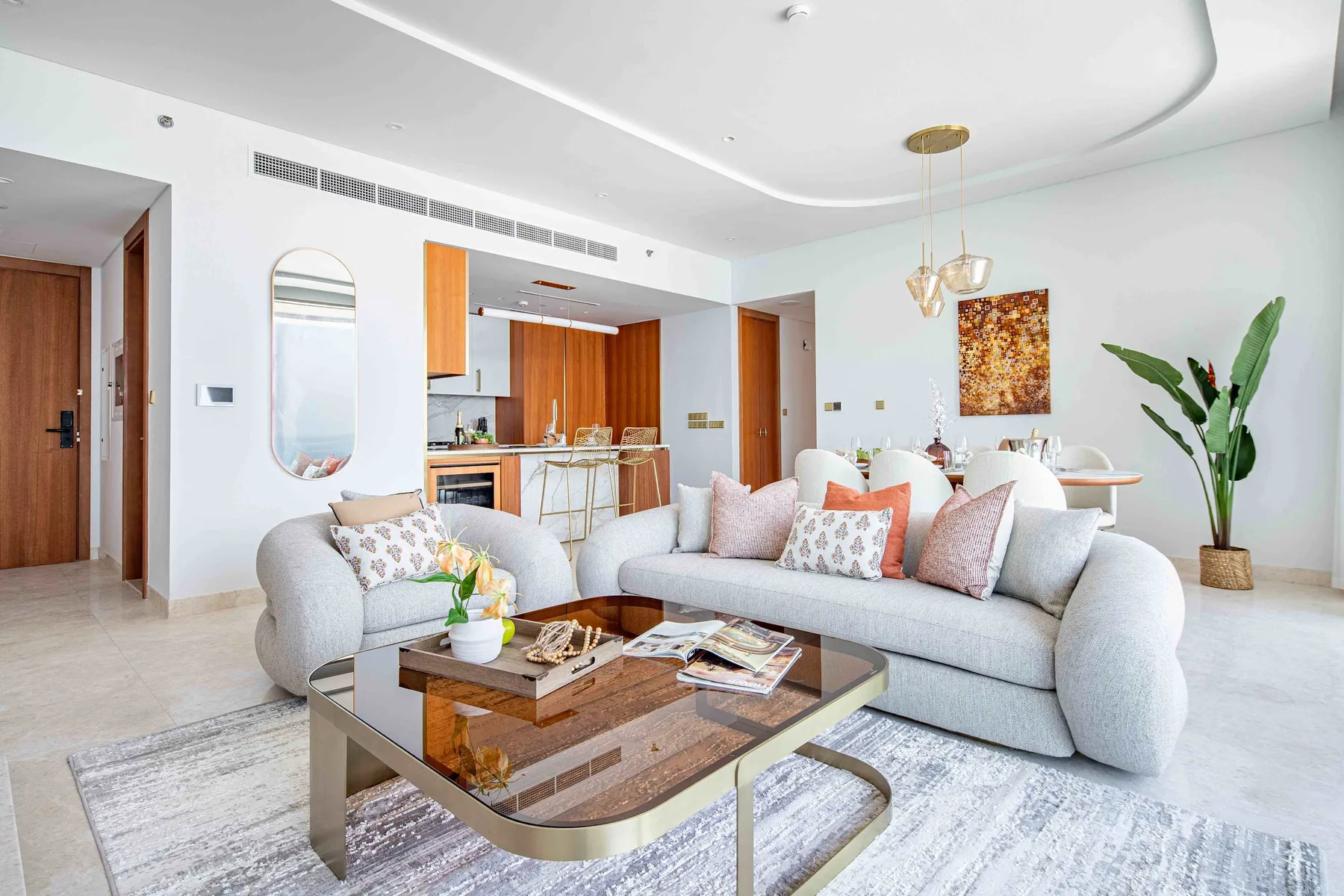 Una sala luminosa con un sofá seccional claro y una mesa de centro de vidrio.