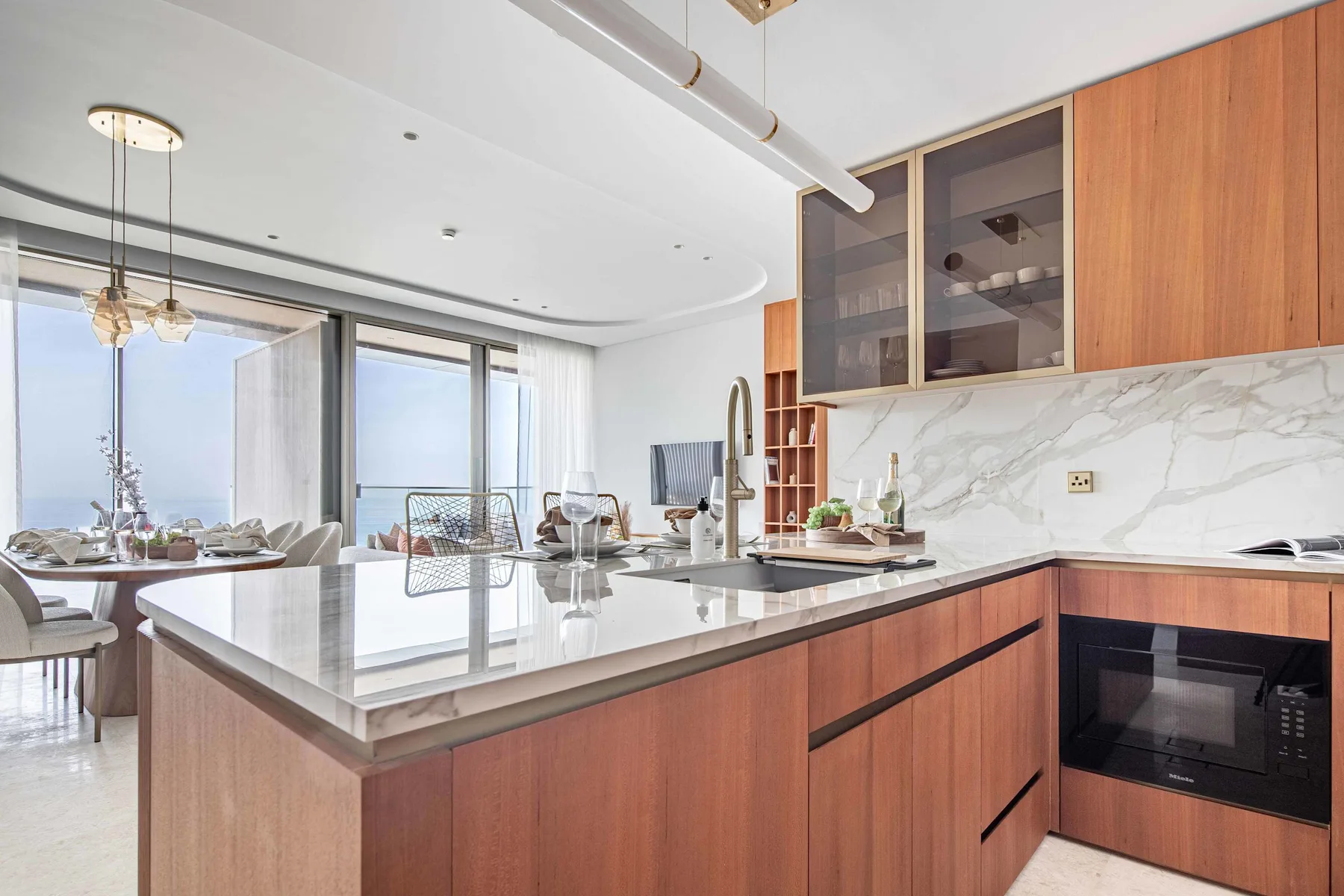 Una cocina moderna con isla central, gabinetes de madera y ventanas amplias.