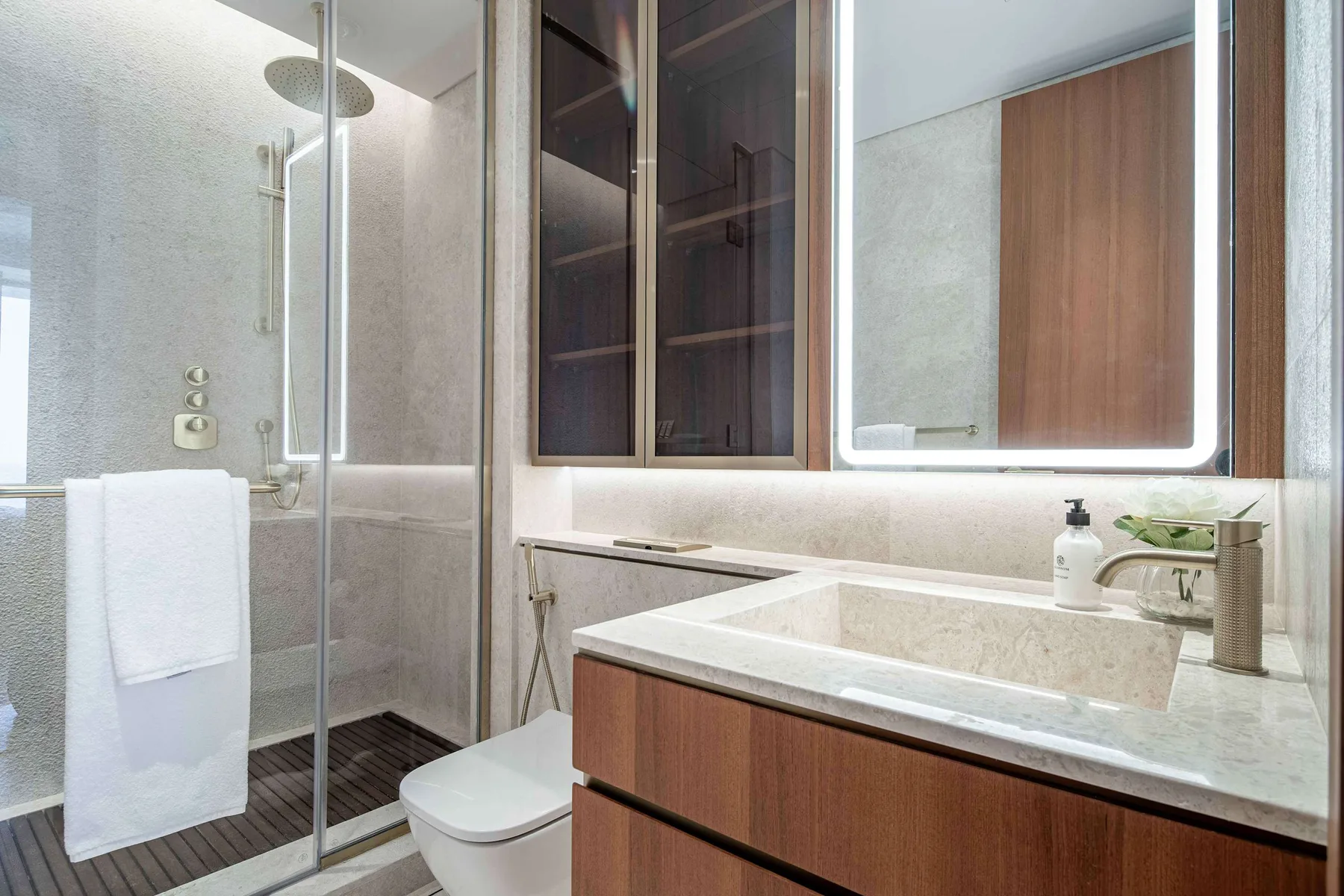 Un baño moderno con ducha de vidrio, inodoro y un amplio tocador.