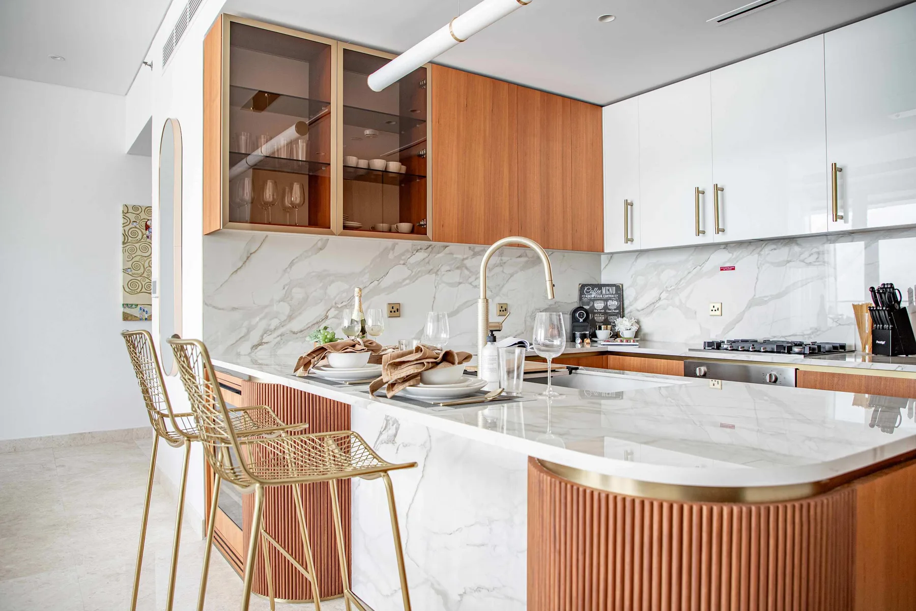 Una cocina moderna y luminosa cuenta con una isla de mármol y asientos tejidos.