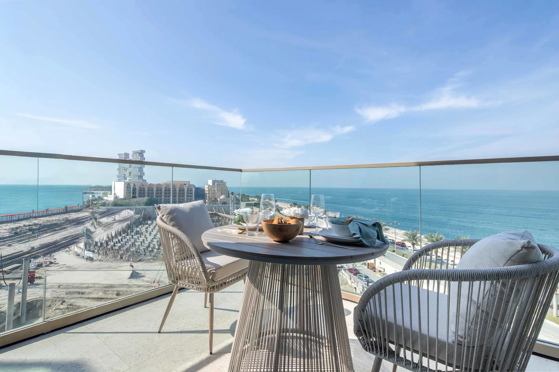 Una zona de comedor en una terraza con vistas al mar, con mesa y asientos al aire libre.