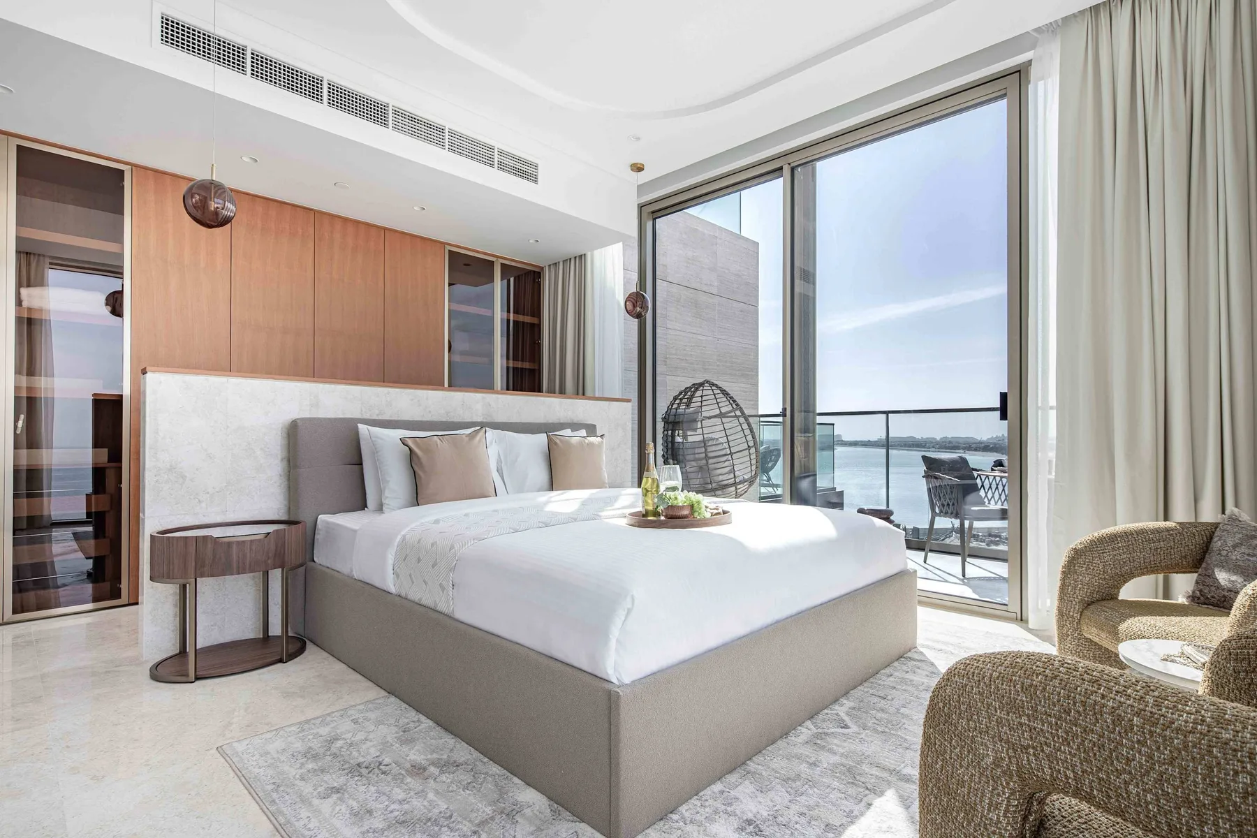 Un dormitorio luminoso con una cama grande junto a ventanales con vistas al agua.