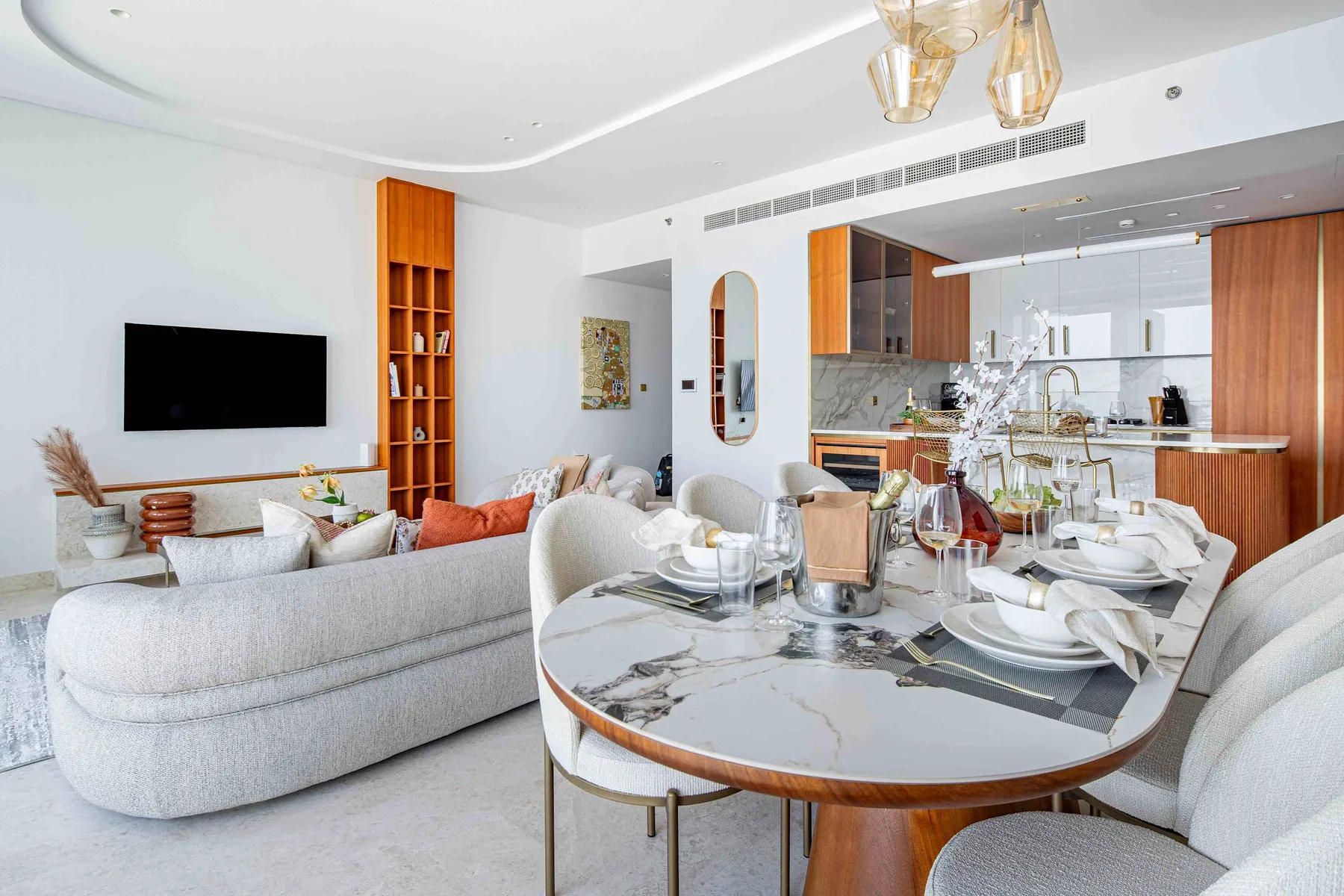 Sala de estar y comedor de planta abierta, con una mesa redonda y la cocina al fondo.