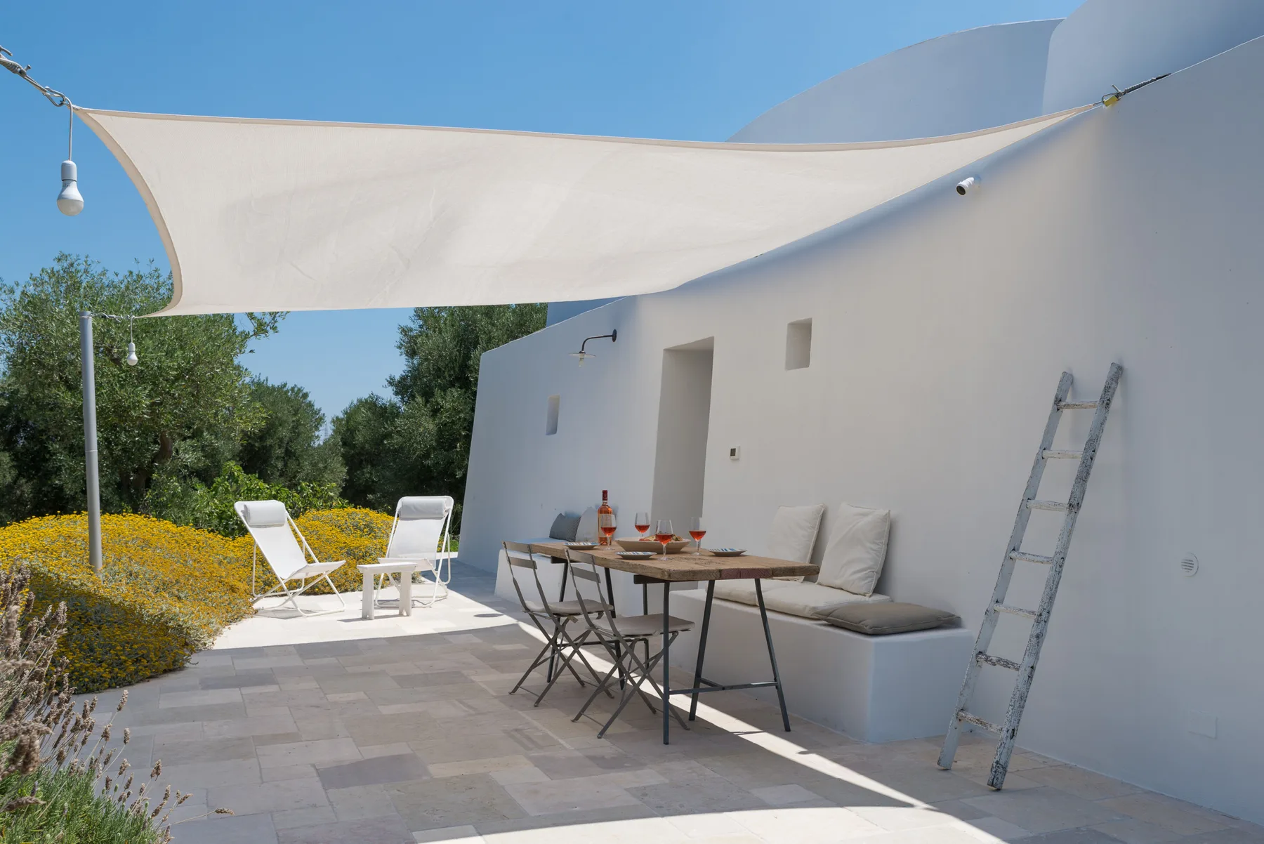Un patio al aire libre con una mesa de comedor a la sombra y asientos integrados.