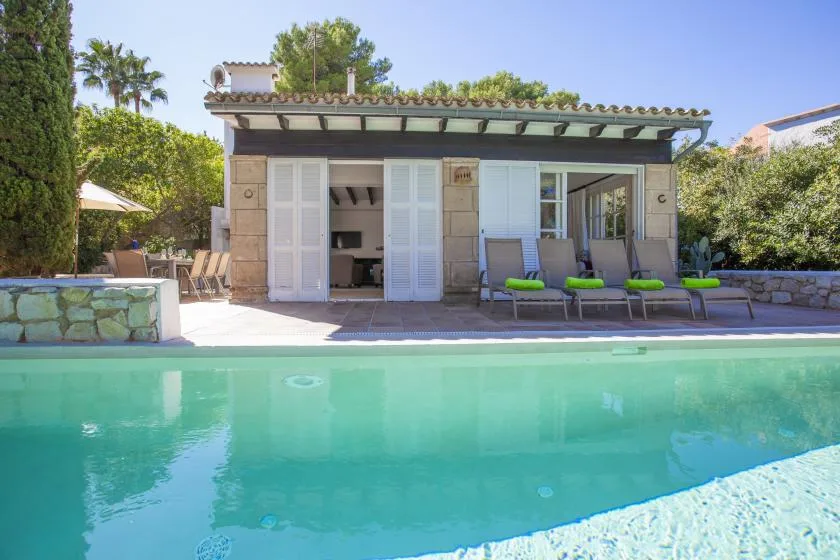 A swimming pool in front of a small building with outdoor seating.
