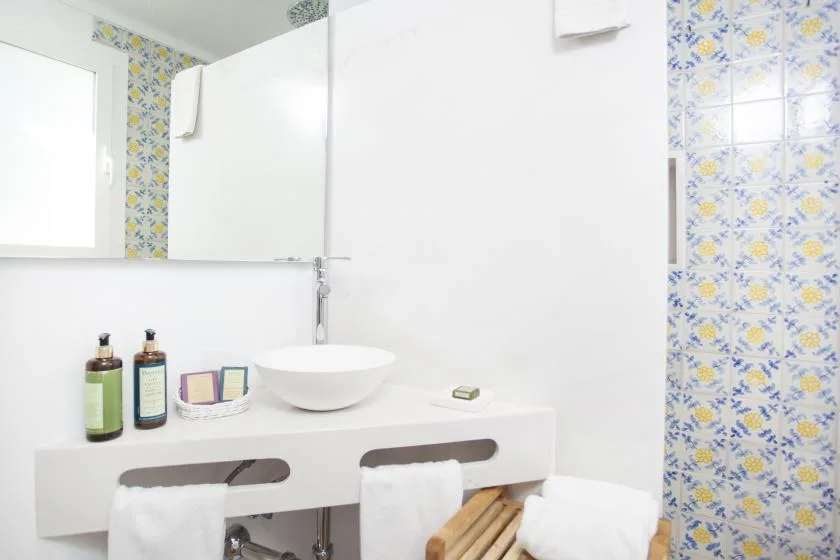 A bright bathroom vanity with a vessel sink and patterned tile walls.